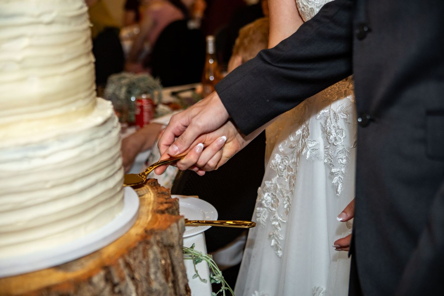 Bride and groom cutting a white wedding cake together at their reception venue.