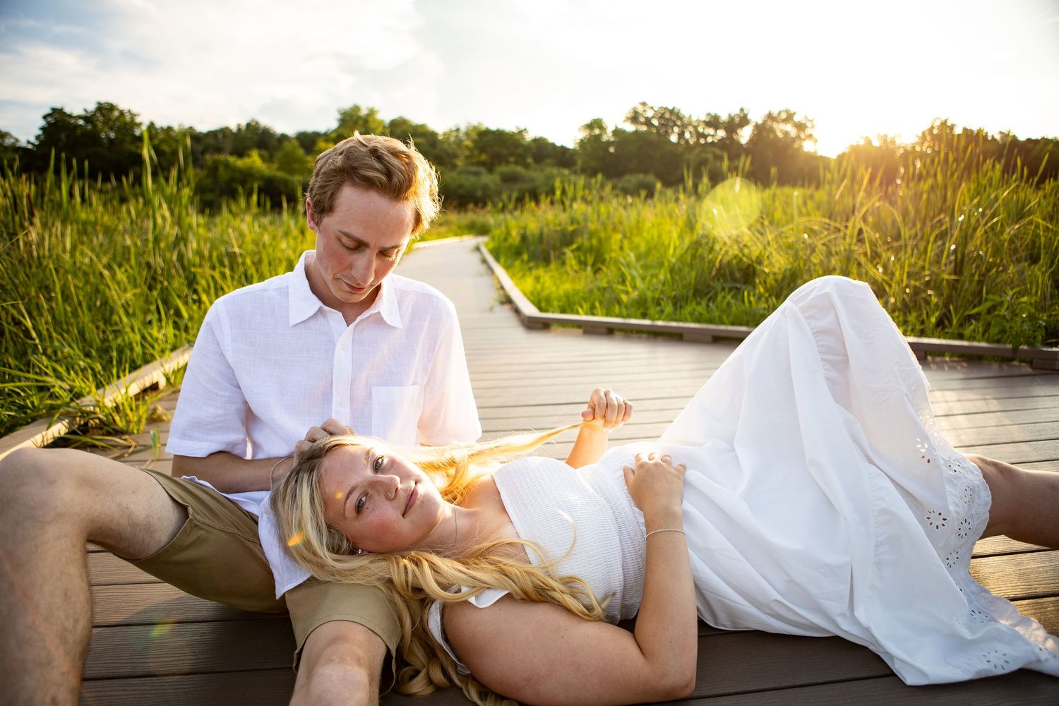 Romantic engagement photos on a wooden boardwalk at sunset.