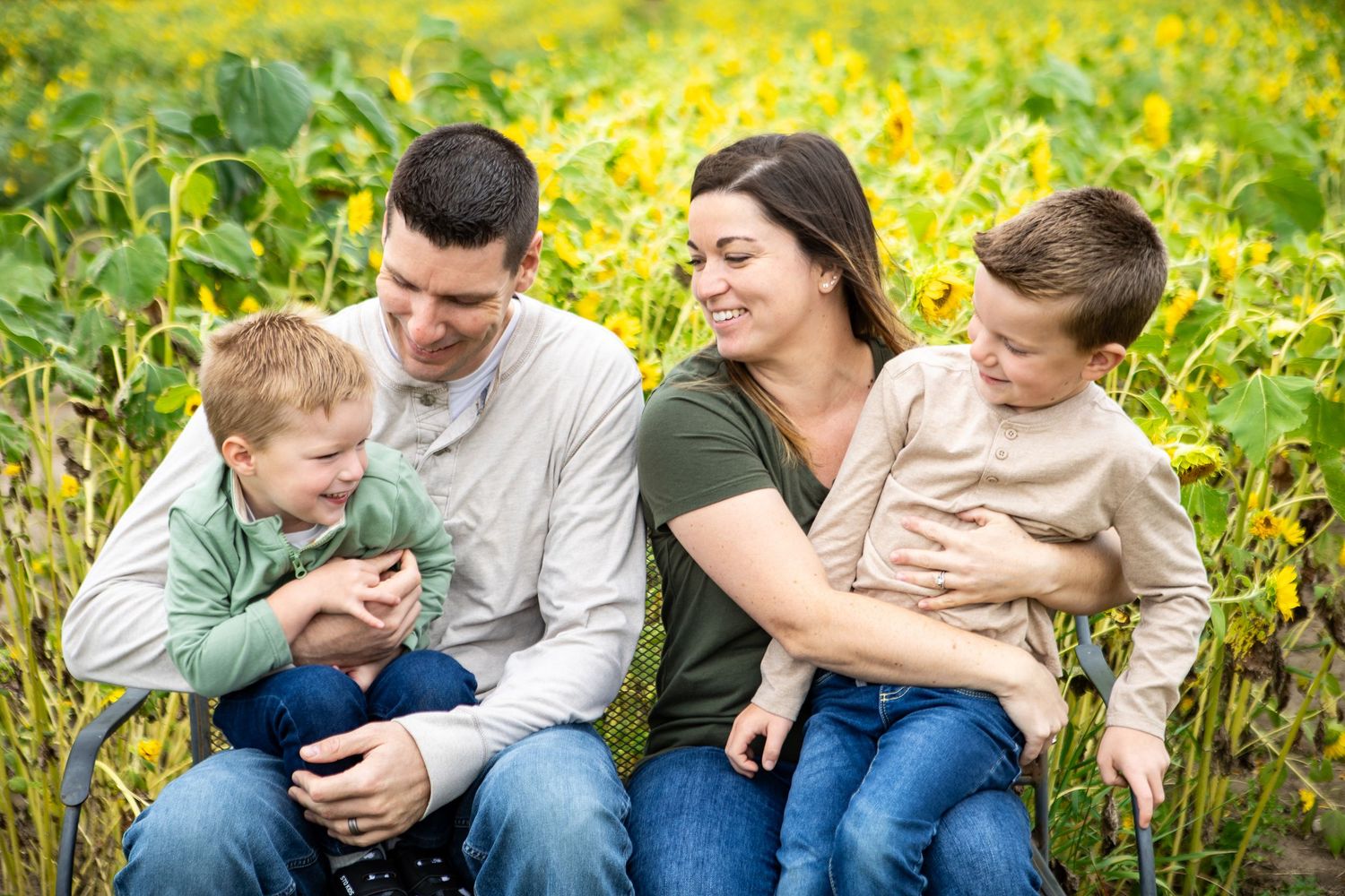 Family lounging together in a field of yellow wildflowers during a casual outdoor photo session.