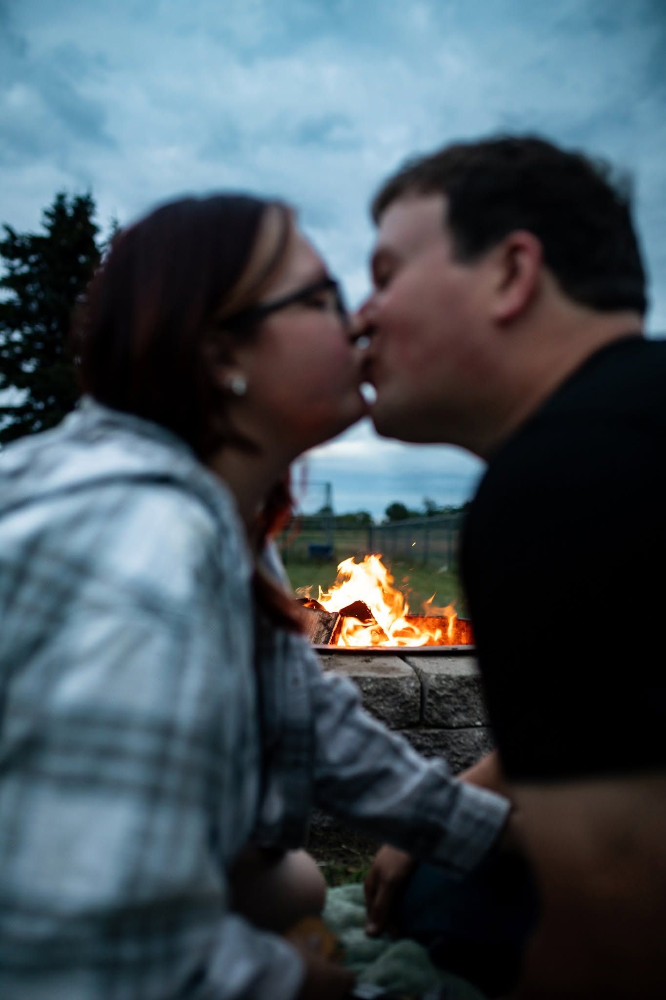 Romantic silhouettes against a blue sky with a bonfire glowing in the background.