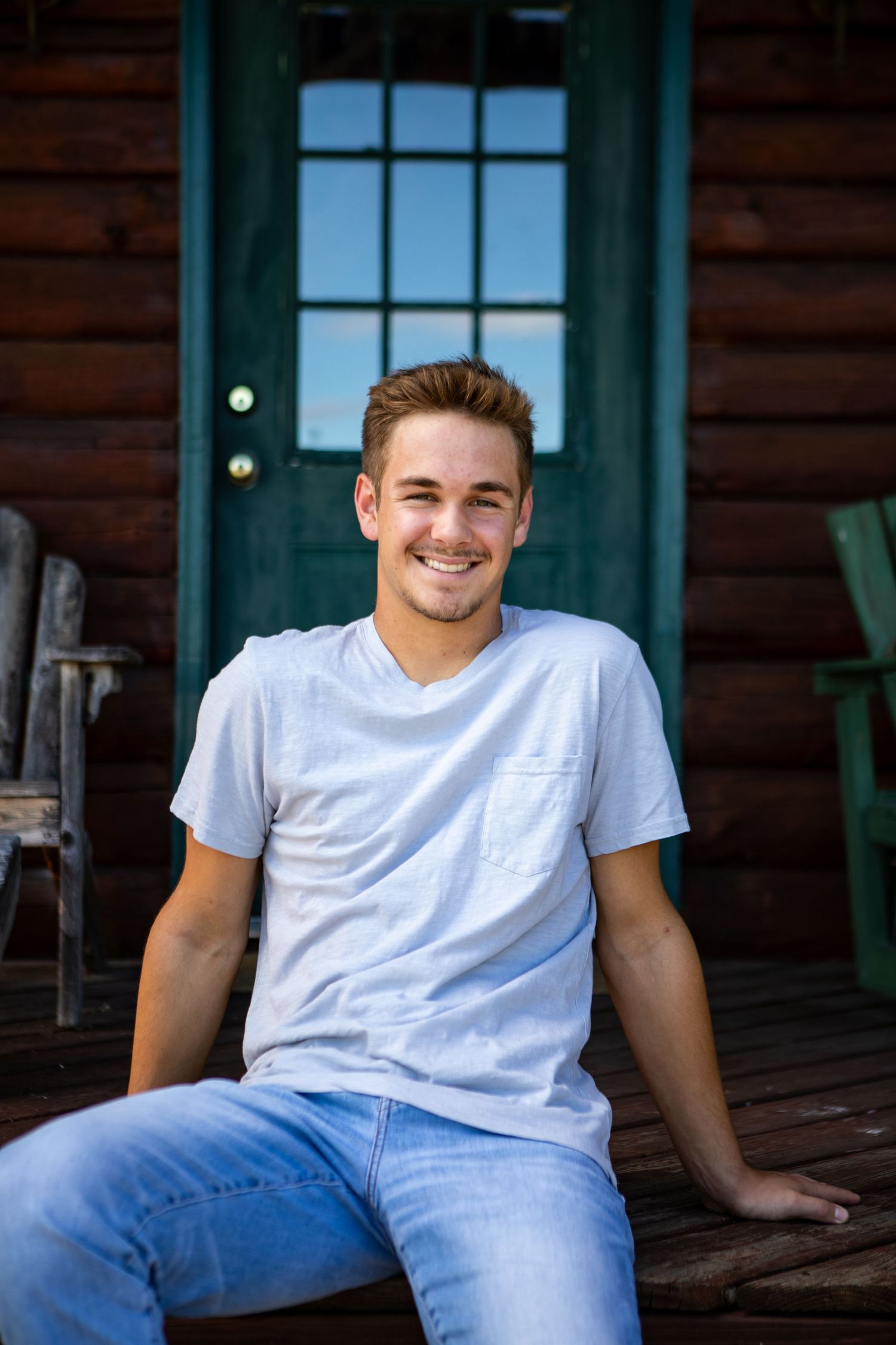 Person relaxing on a rustic cabin porch in casual attire.