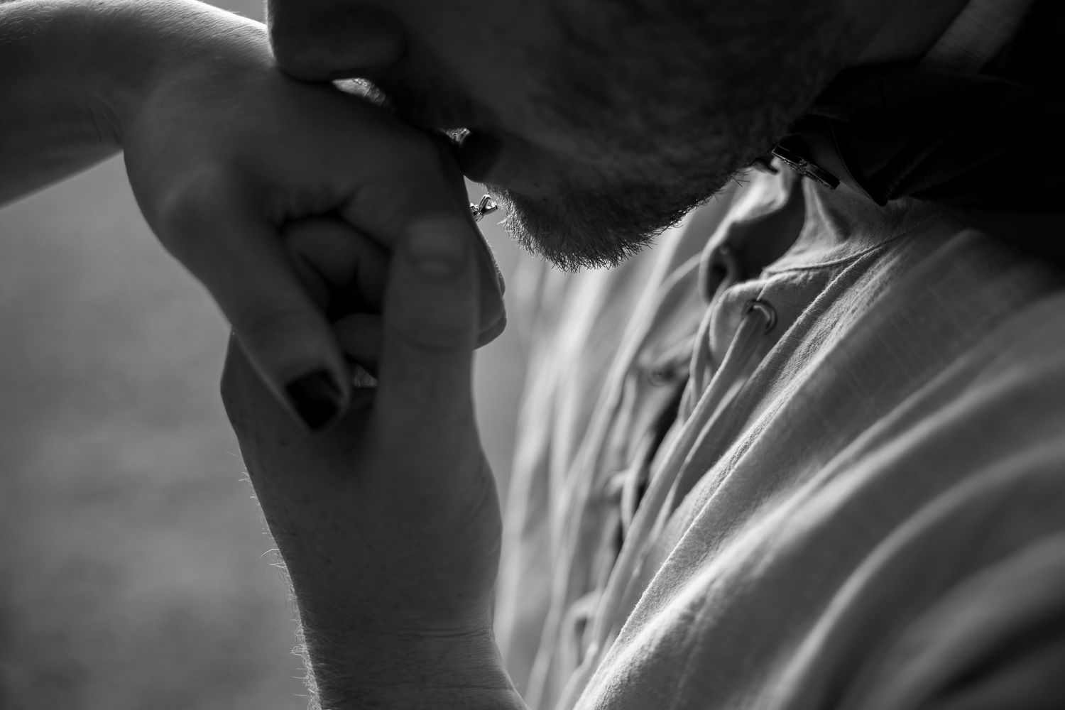 Black and white photo of a bearded man bowing his head in prayer or deep thought, close-up portrait.