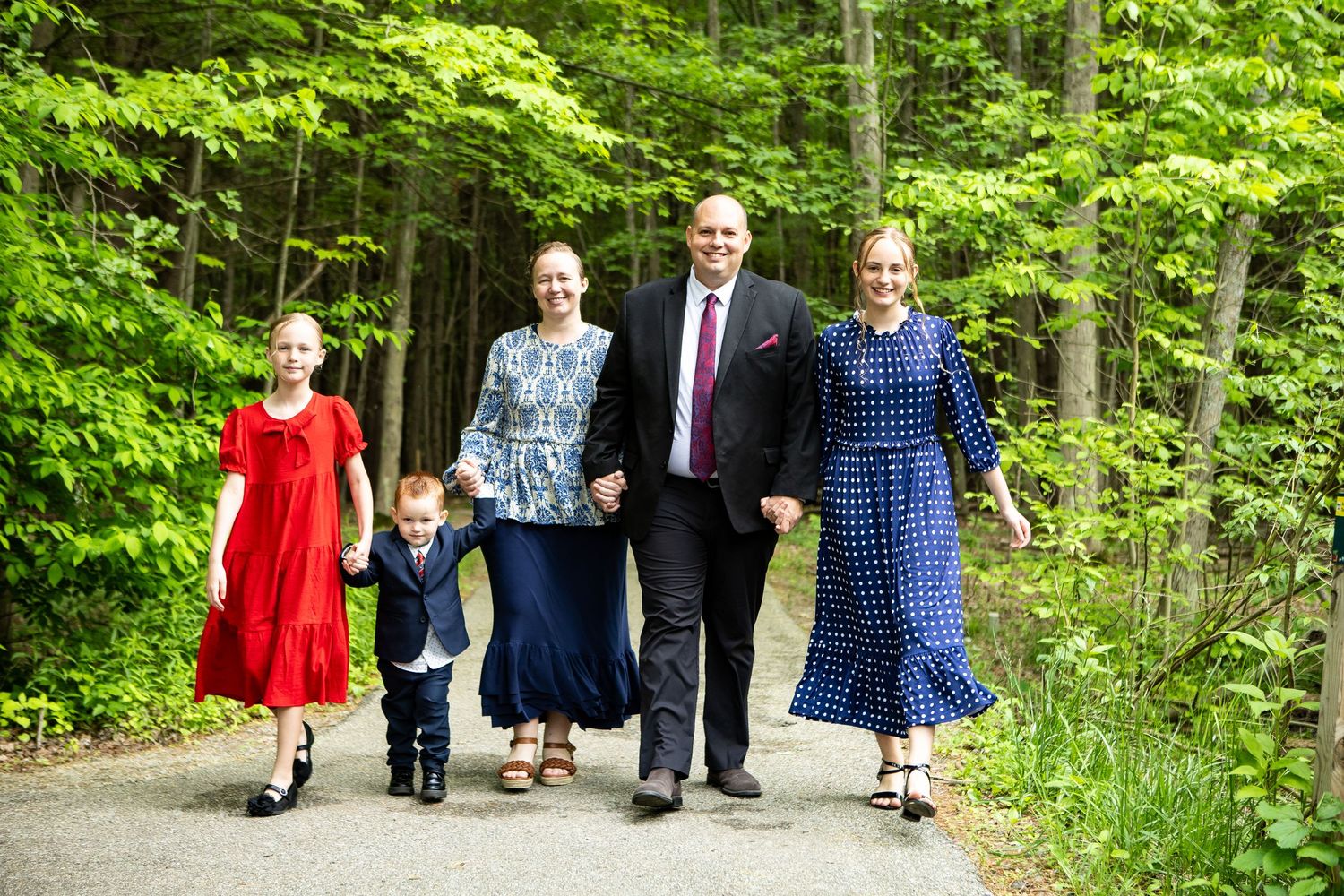 Family members walking together on wooded path wearing coordinated outfits.