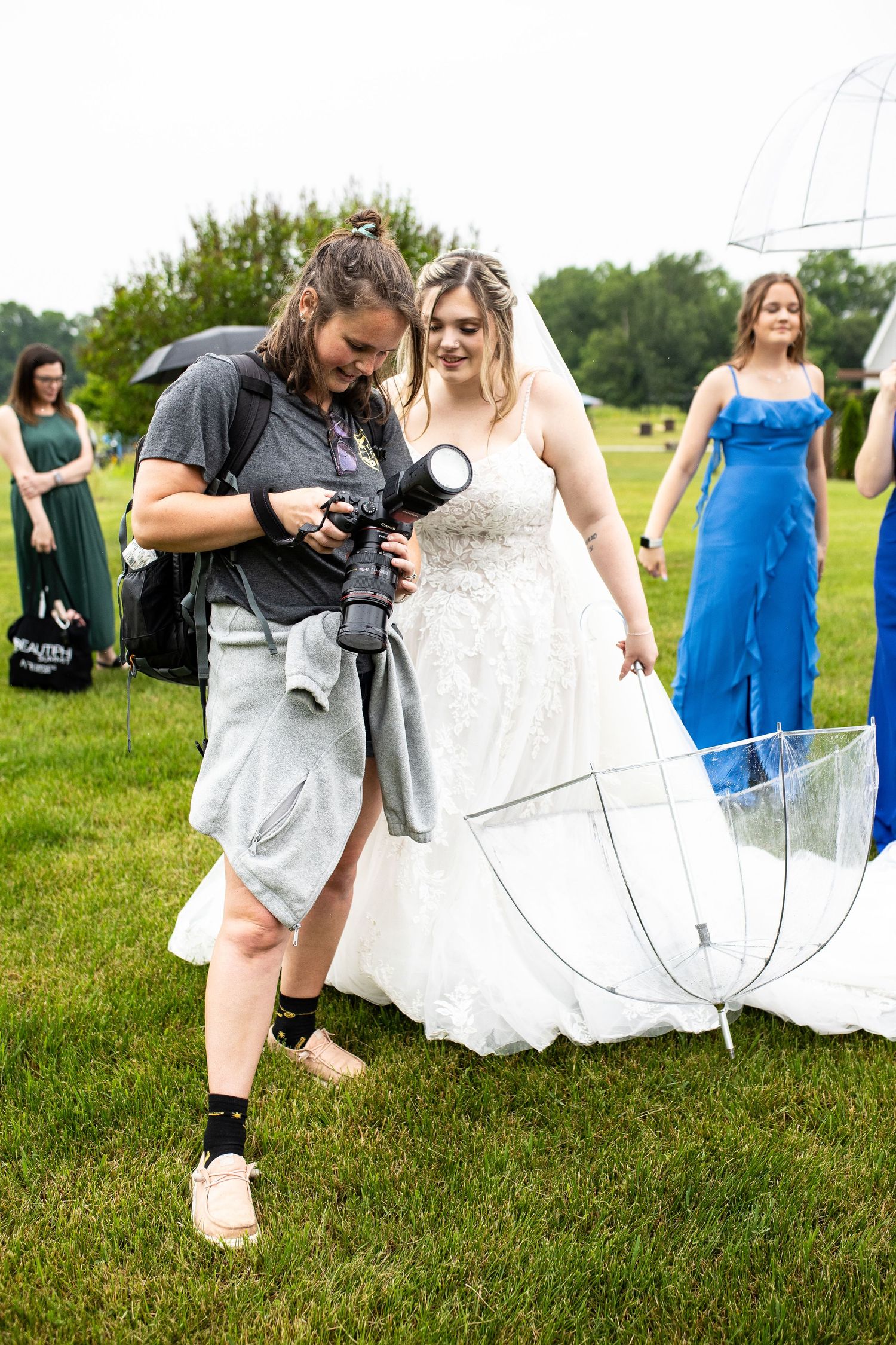 Photographer reviewing camera settings during outdoor wedding photoshoot.