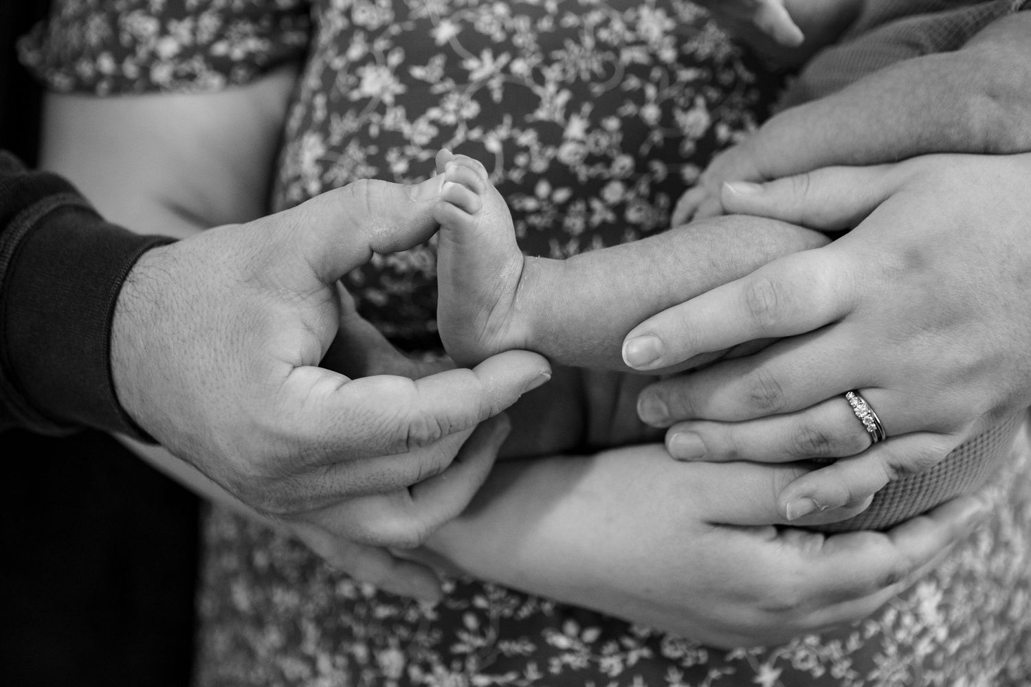 Black and white close-up of hands holding newborn.