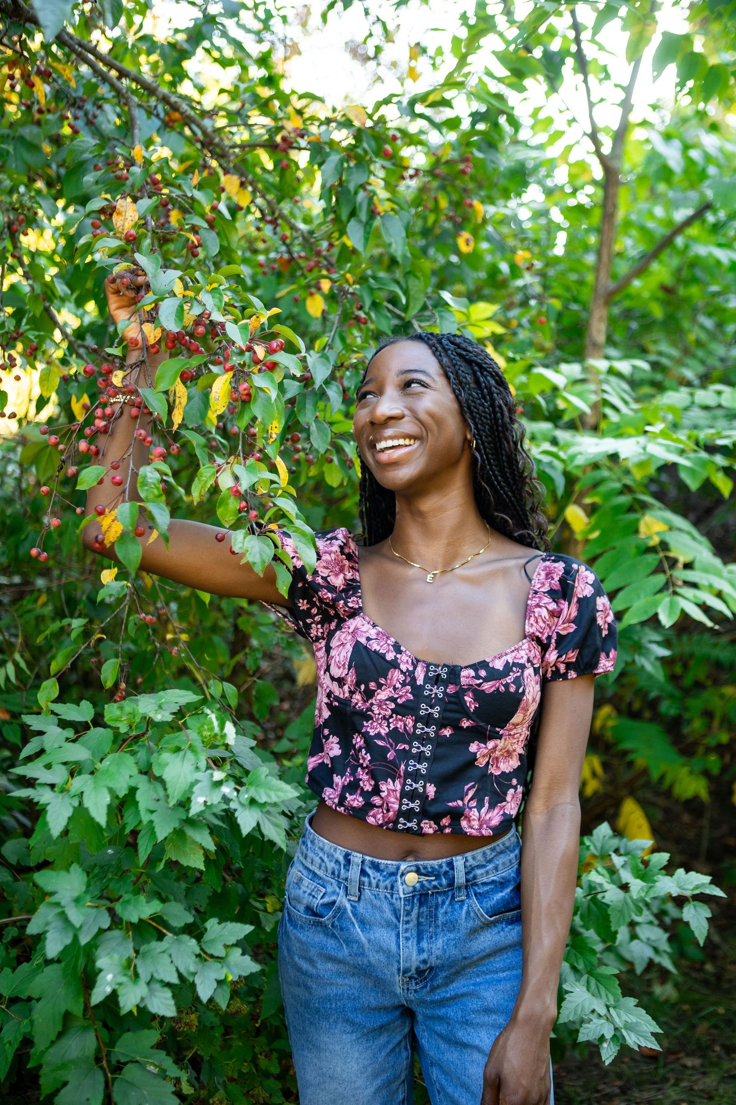 A joyful summer photoshoot in a lush garden setting wearing a floral crop top and blue jeans.