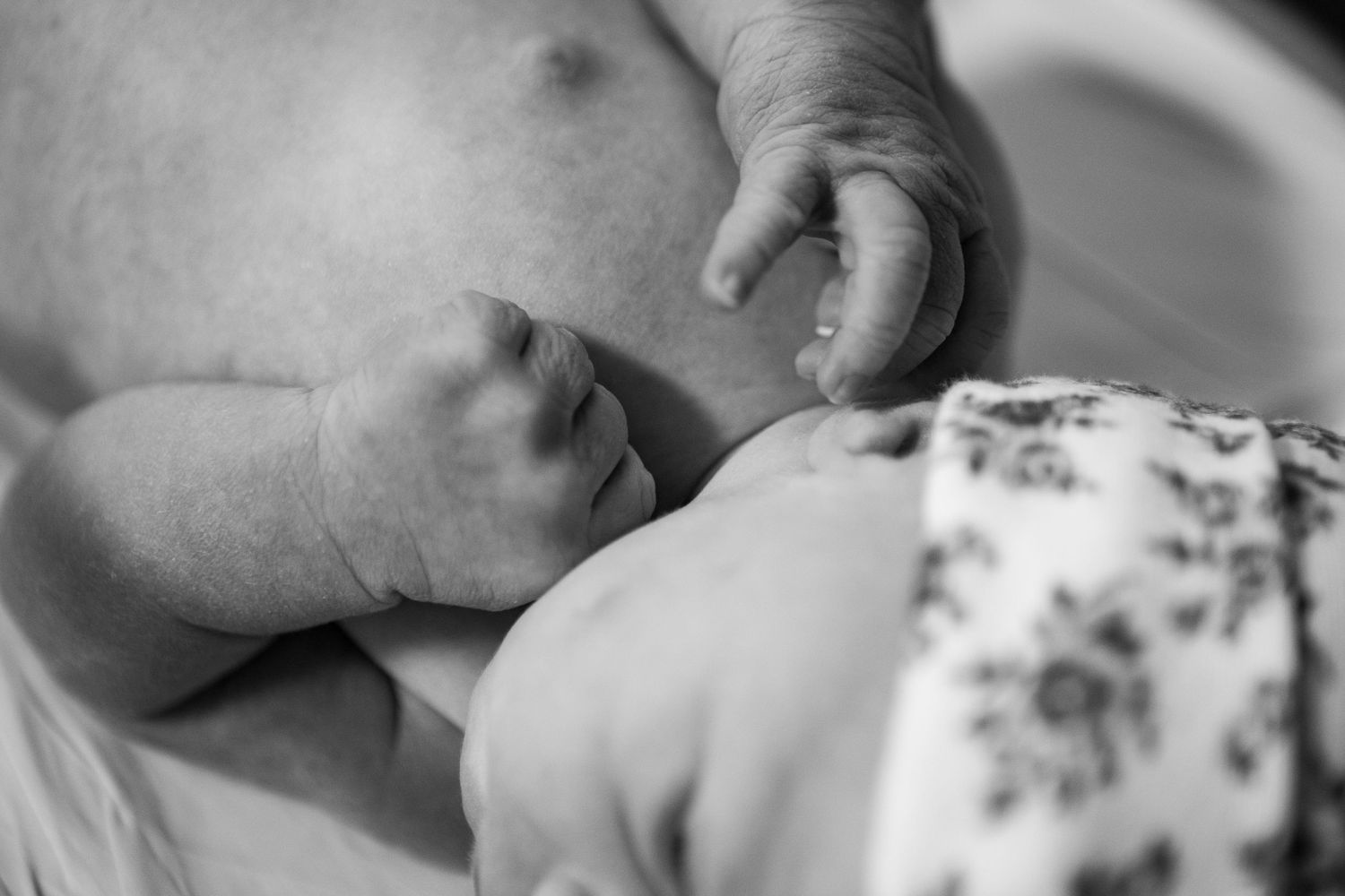Close-up view of newborn baby details in soft black and white tones.