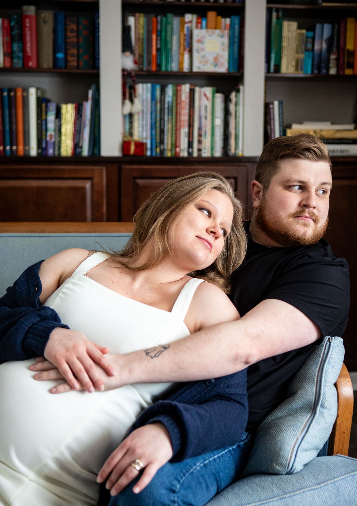 Couple relaxing together on couch with bookshelf background.