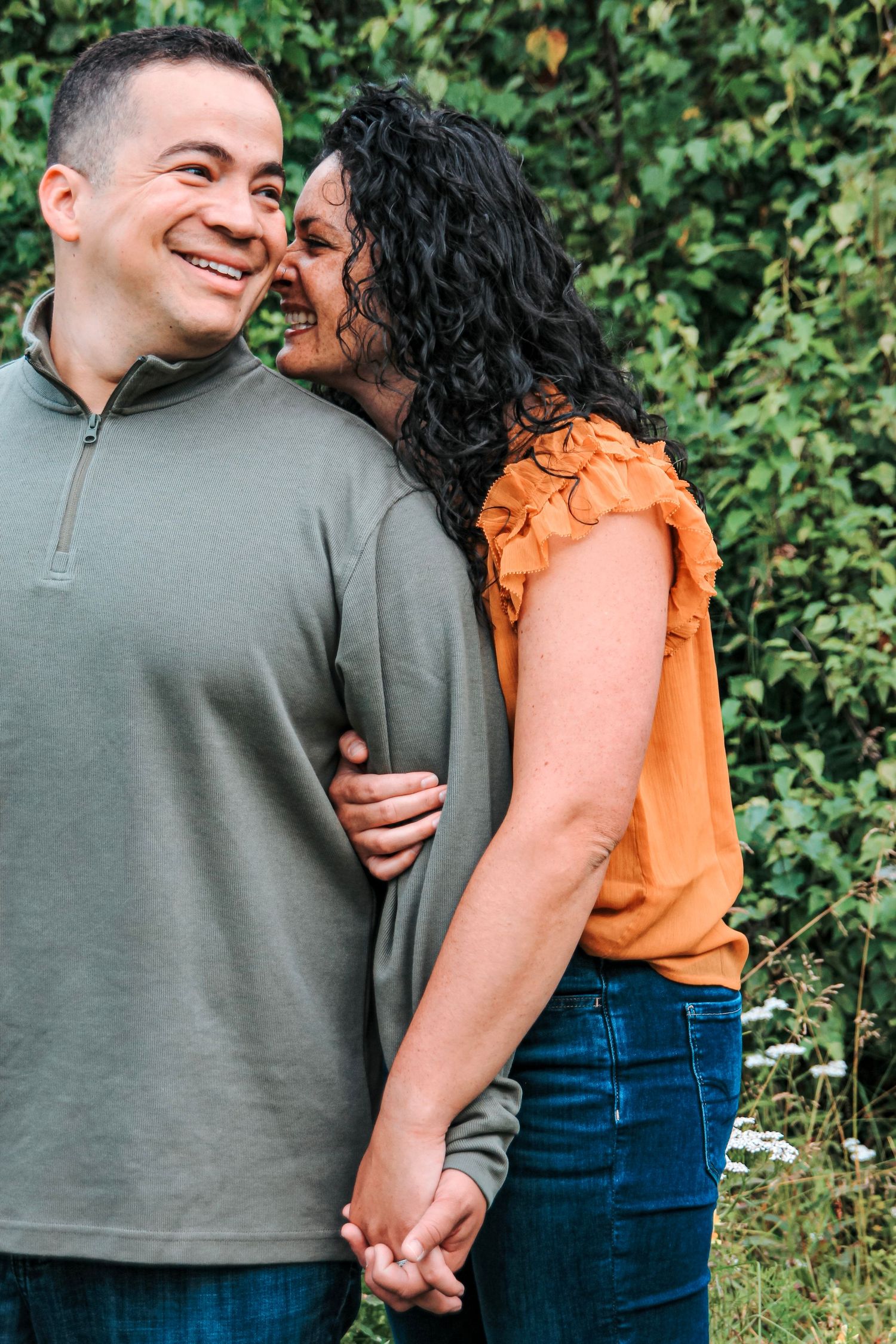 Couple holding hands and laughing together during a relaxed outdoor lifestyle photography session.