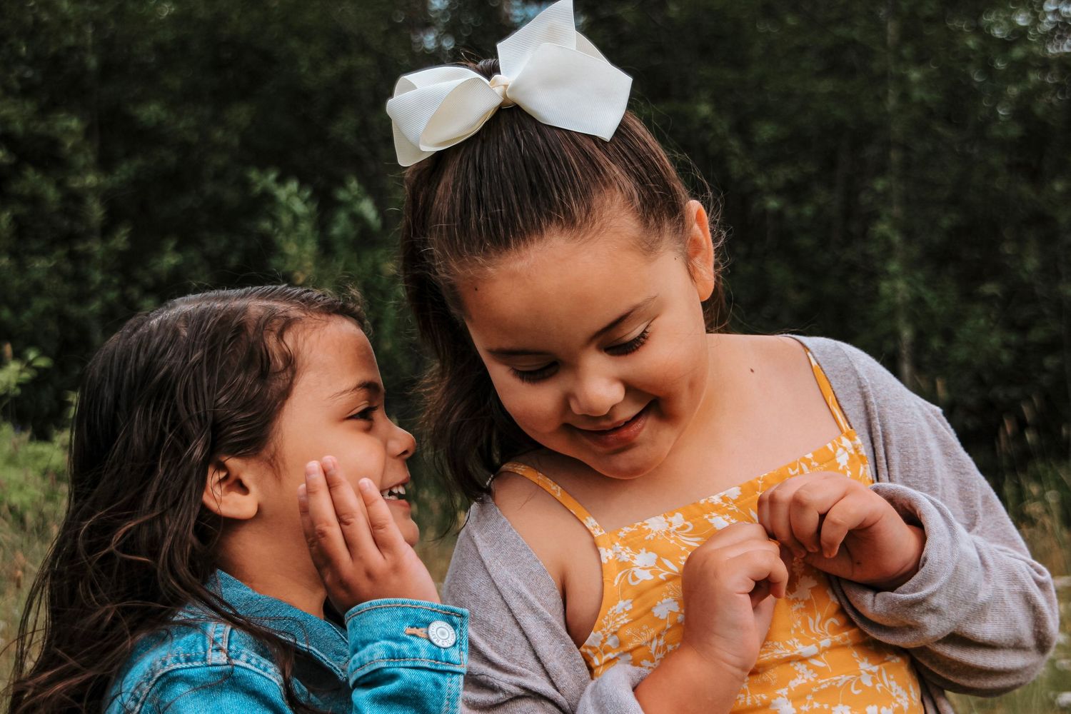 Two young children sharing a sweet moment and smiling together during an outdoor lifestyle session.