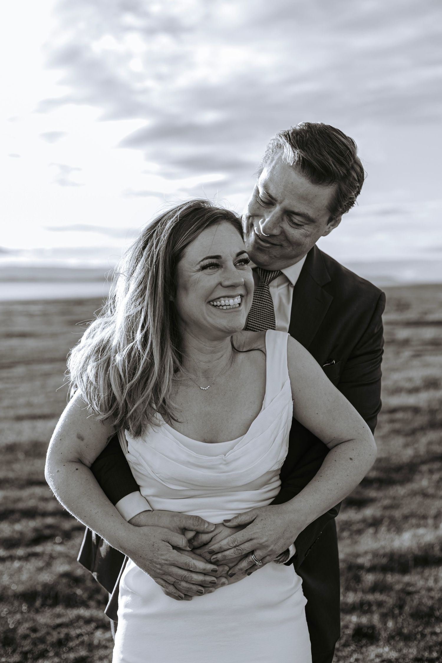 Intimate black and white portrait of a bride and groom embracing in an open Alaska field.