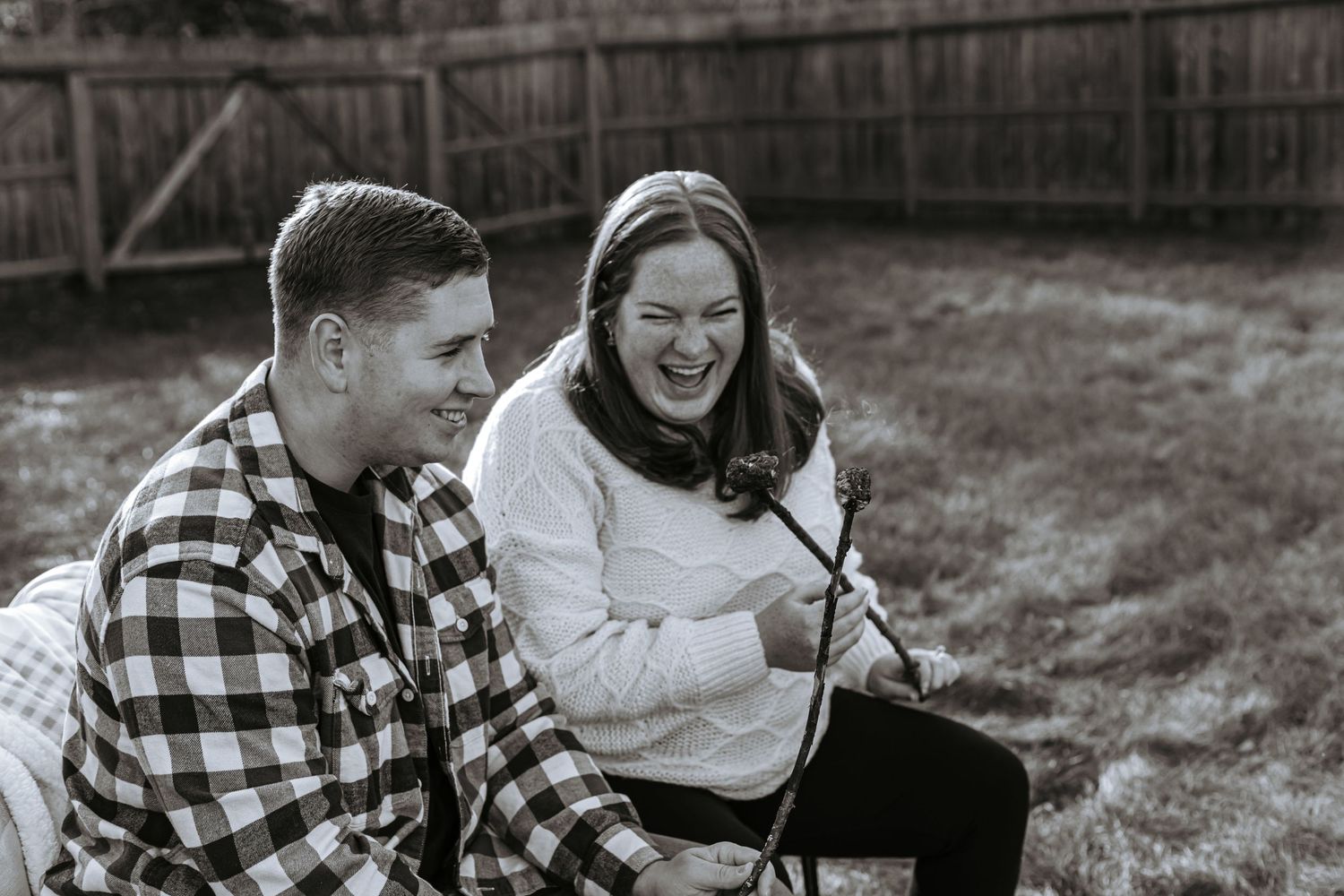 Black and white lifestyle photo of a couple laughing together during a relaxed outdoor session.
