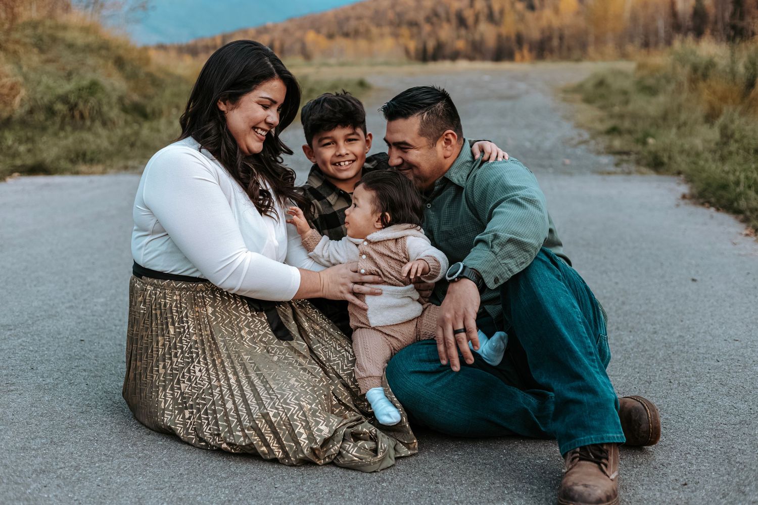 Family sitting together on a quiet road during a warm, candid outdoor photography session.