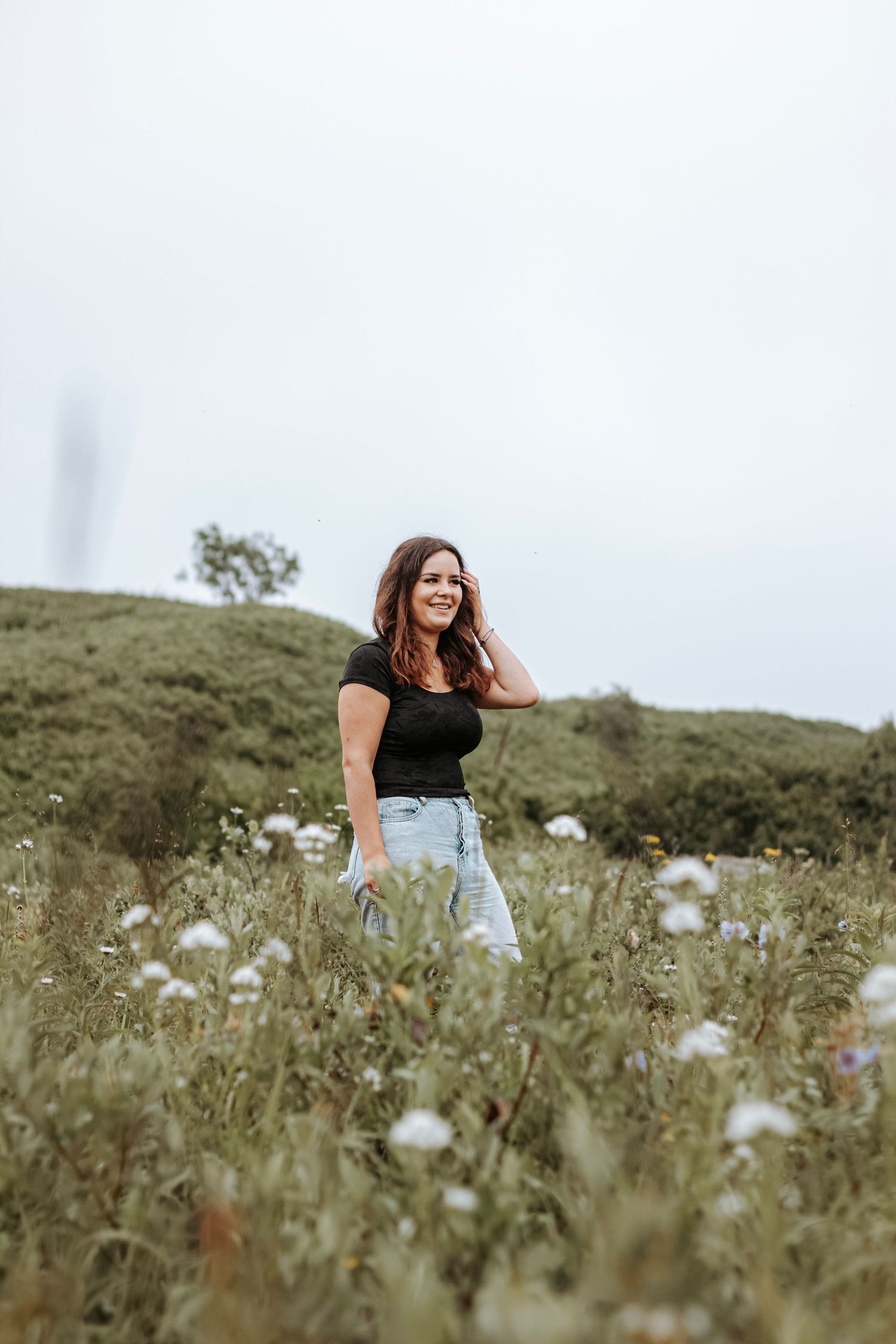 Senior portrait of a young woman standing in a wildflower field in Alaska during a natural outdoor session.