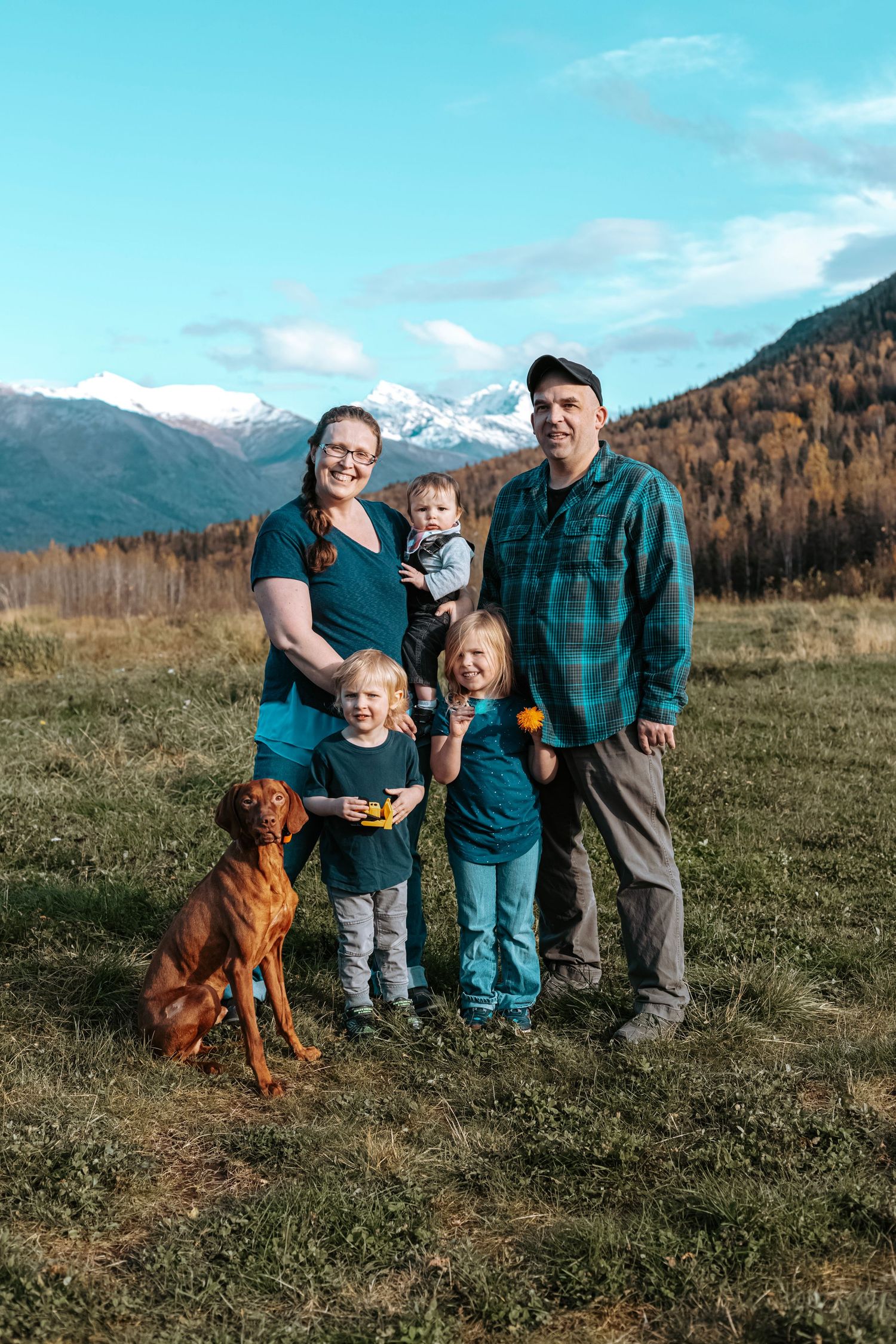 Family and dog photographed in front of Alaska mountains