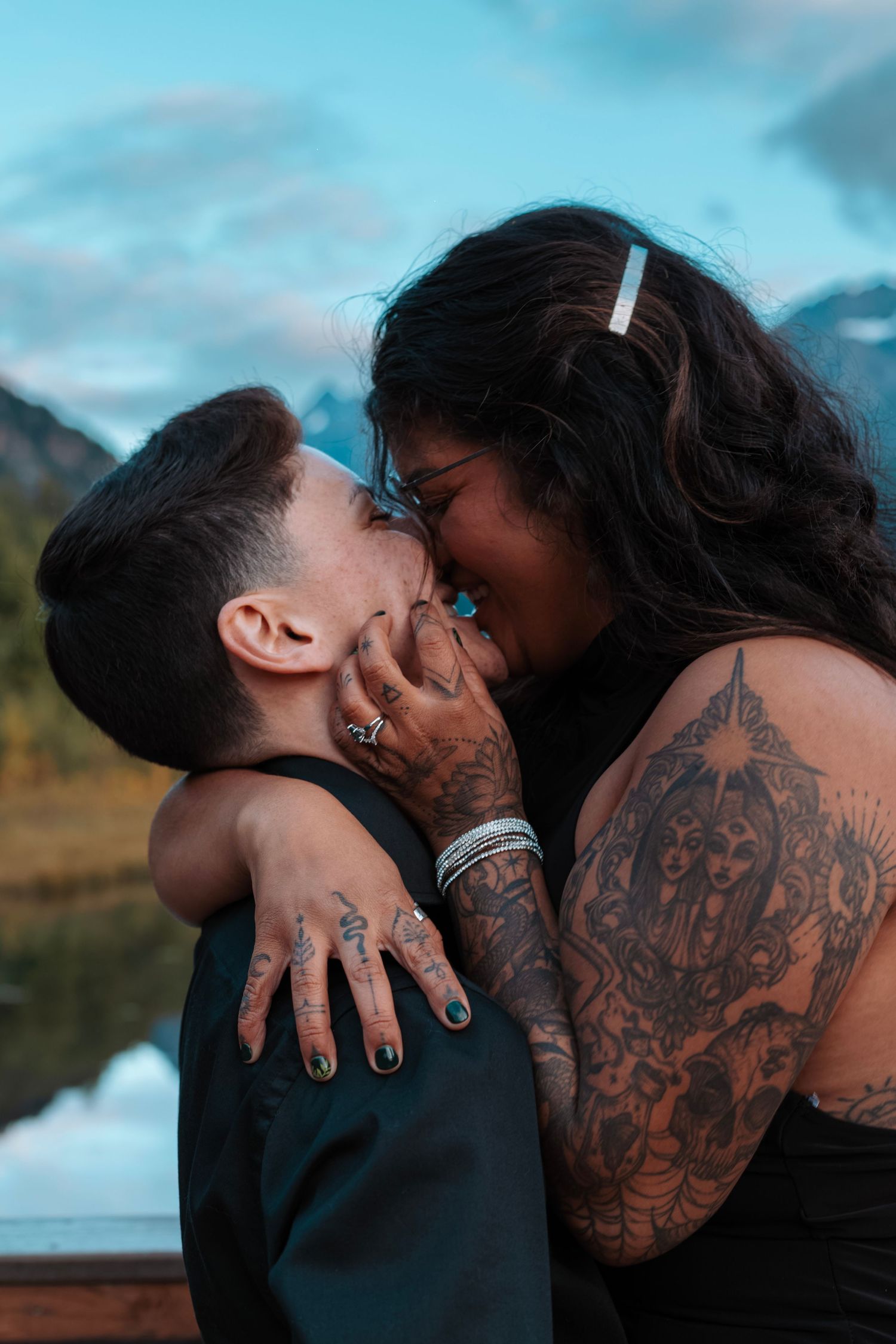 Emotional elopement portrait of a couple sharing a kiss by the water in the Alaska wilderness.