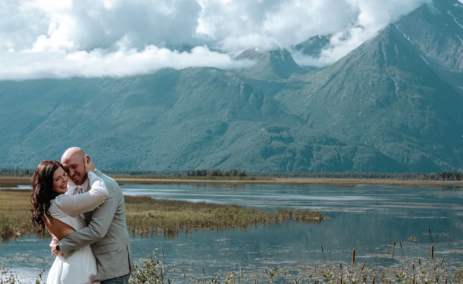 Bride and groom embracing during an Alaska elopement with dramatic mountain scenery in the background.