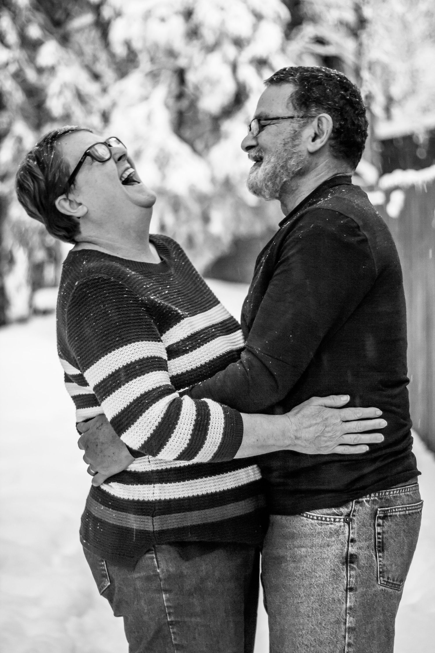 Black and white lifestyle photo of a couple laughing together during an intimate outdoor session.