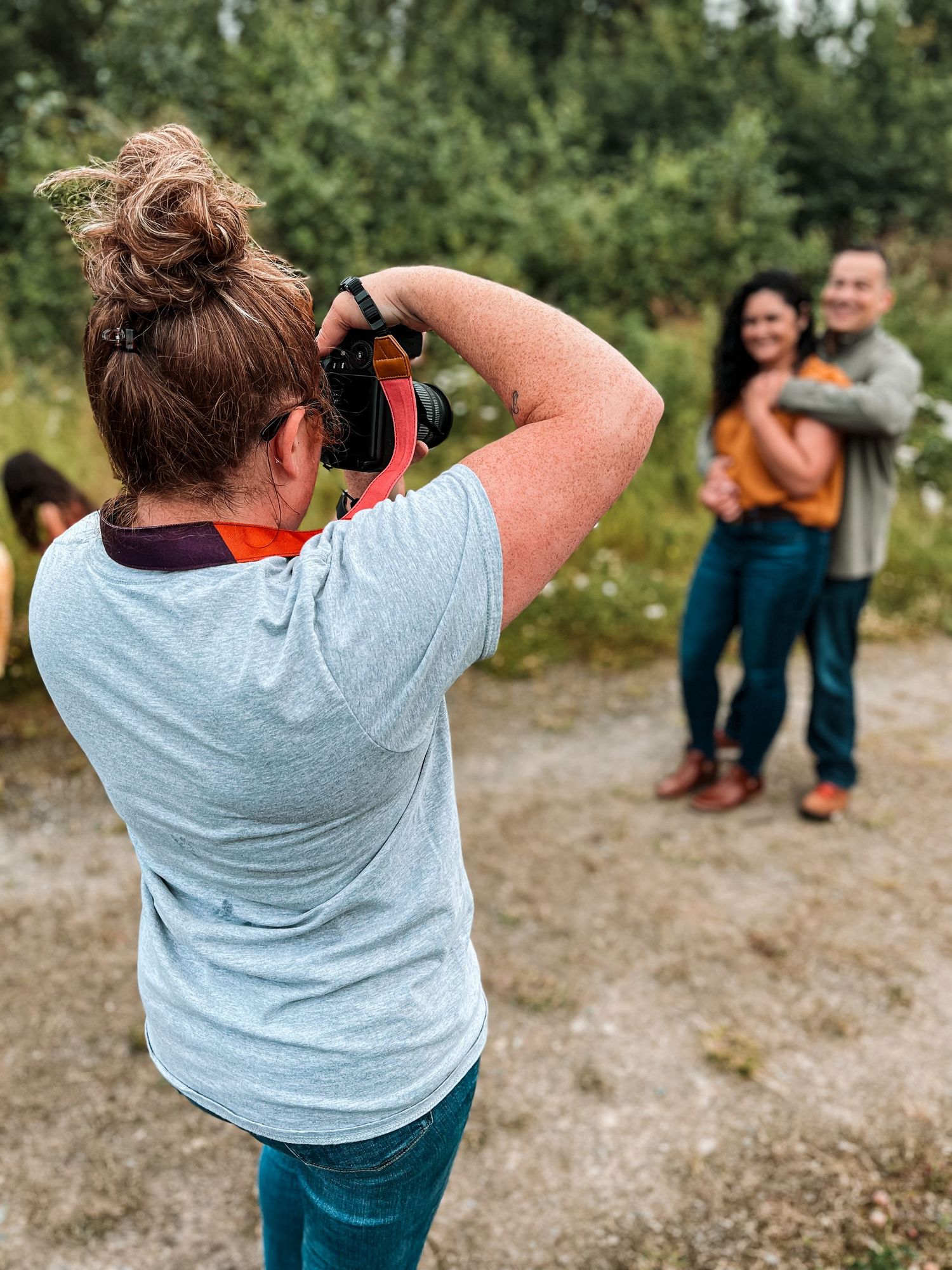 Behind the scenes portrait of photographer taking photos of a couple at an outdoor family session