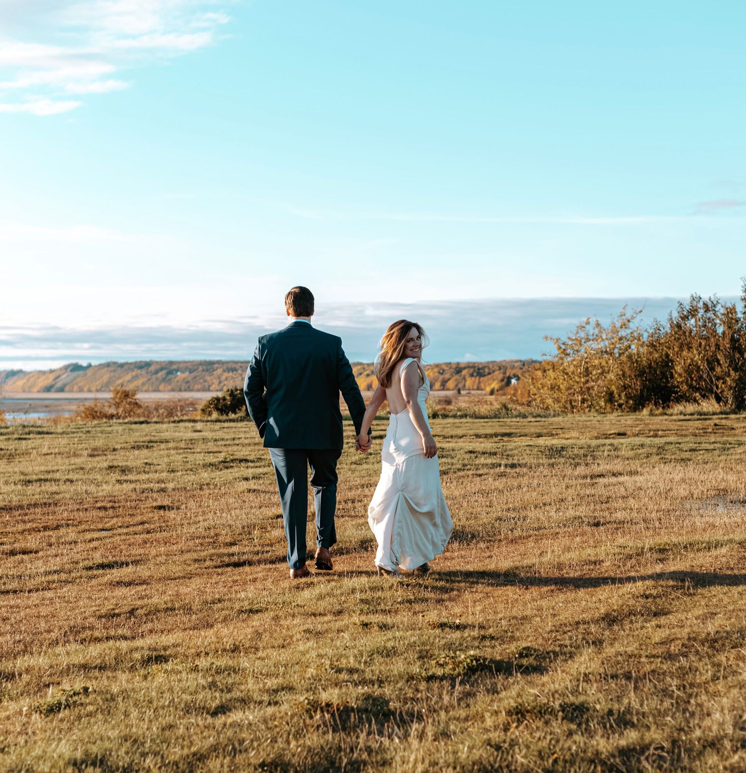 Bride and groom walking hand in hand through an Alaska landscape during an intimate moment.