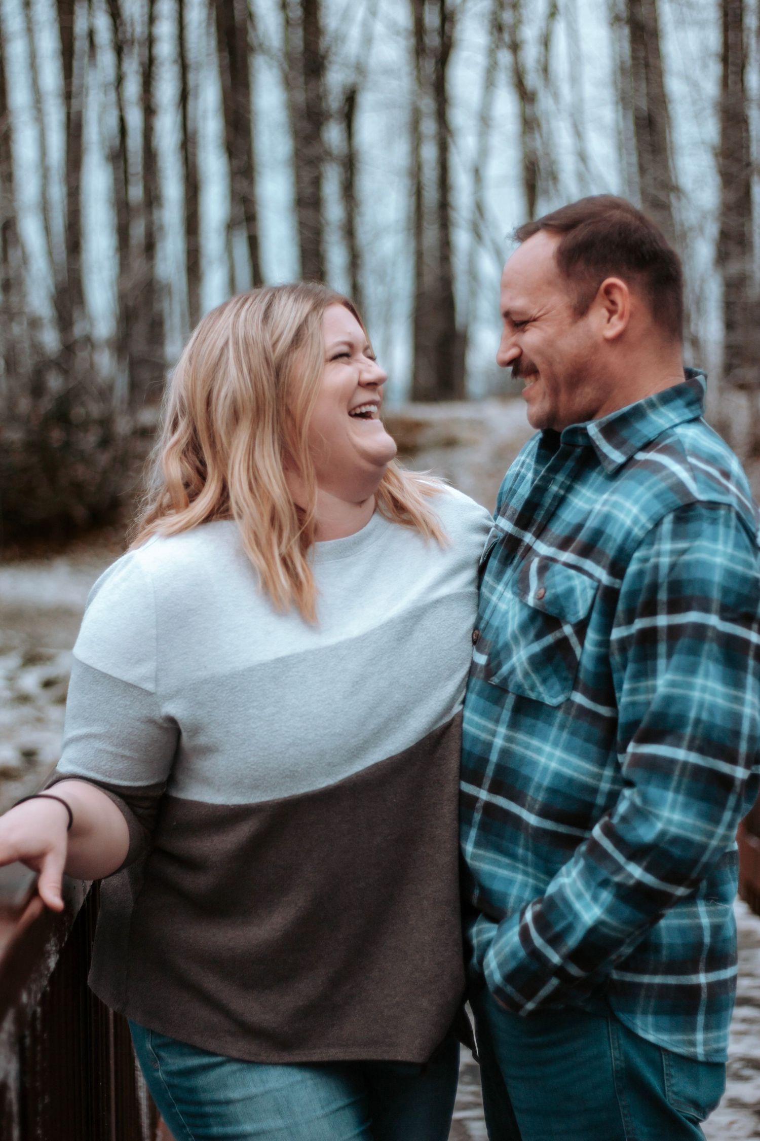 Couple laughing together in a wooded setting during a relaxed family photography session.