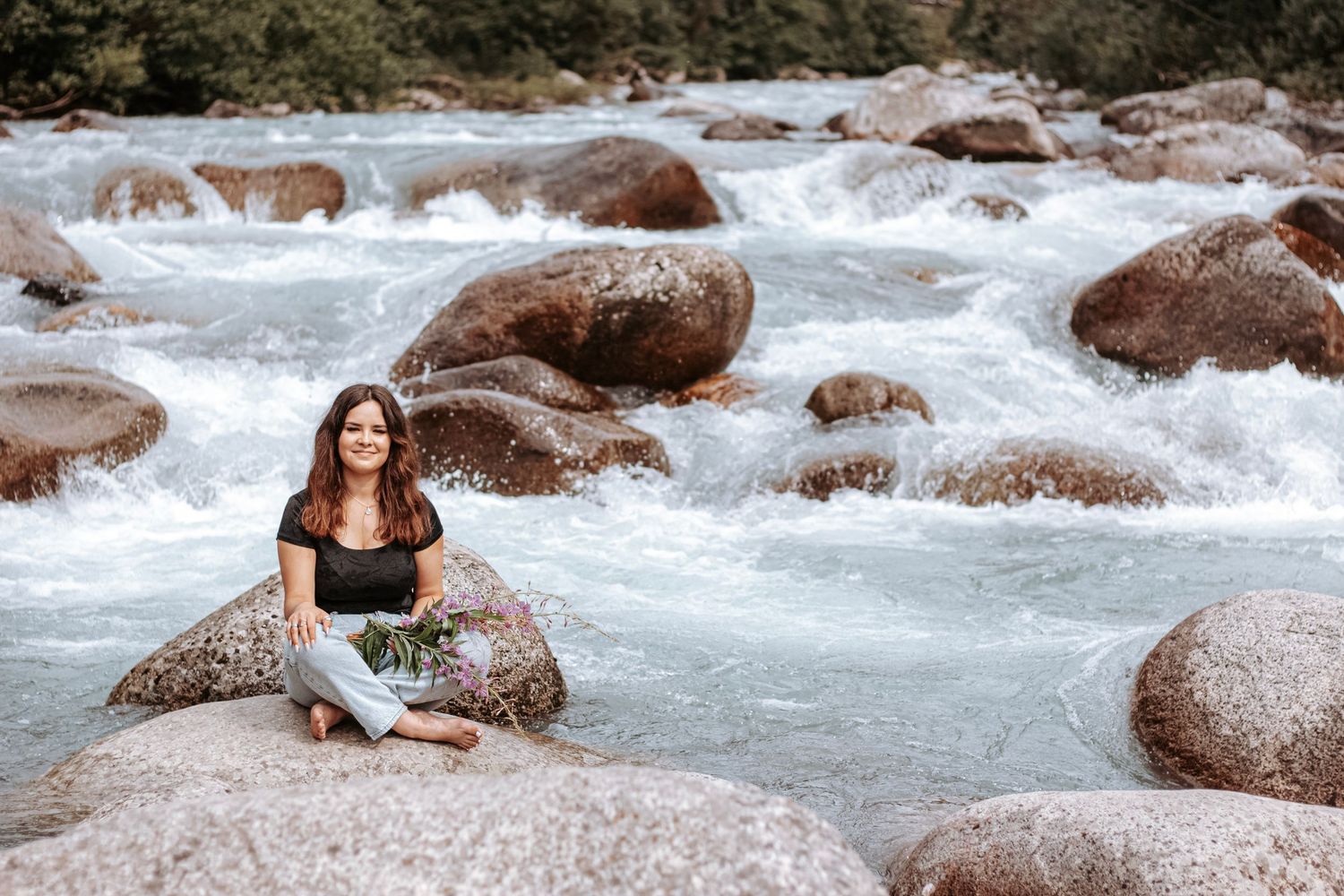 High school senior sitting on a giant rock in a river in Alaska