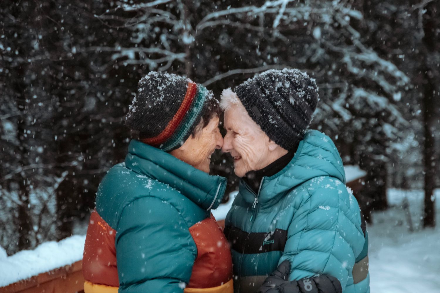 Same sex couple embracing the snowfall and close touches in an Alaskan winter - Smiles captured perfectly by Lucky River Photography