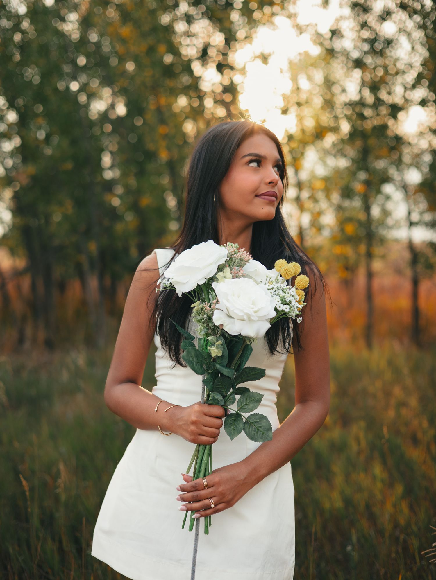 Beautiful white floral bouquet with roses and eucalyptus held against a white dress in golden sunset light. senior photo, Great Falls, MT