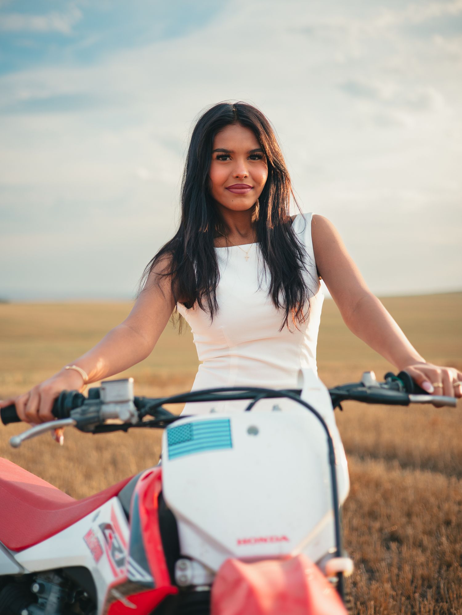 A rider in white clothing sits on a red dirt bike in a vast open field at dusk. photo, Great Falls, MT