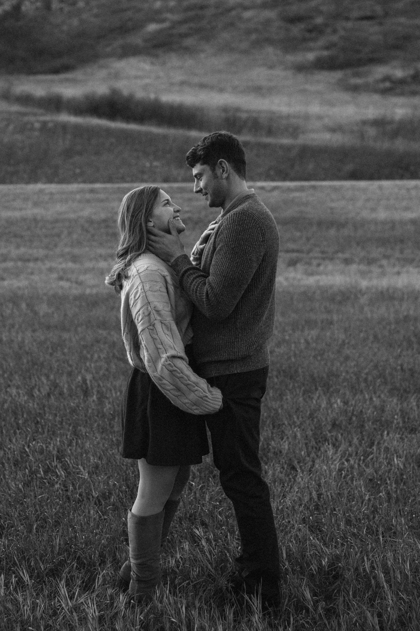 A romantic black and white photo of a couple sharing an intimate moment together in a grassy field. photo, Great Falls, MT
