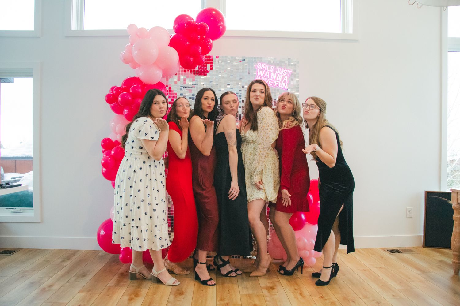 Group photo with pink balloon arch showing friends in formal dresses at celebration. Great Falls, Montana