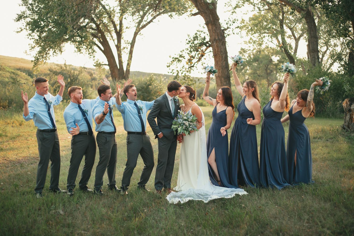 Wedding party in navy blue and white attire poses together outdoors in a natural setting at sunset. photo, Great Falls, Montana