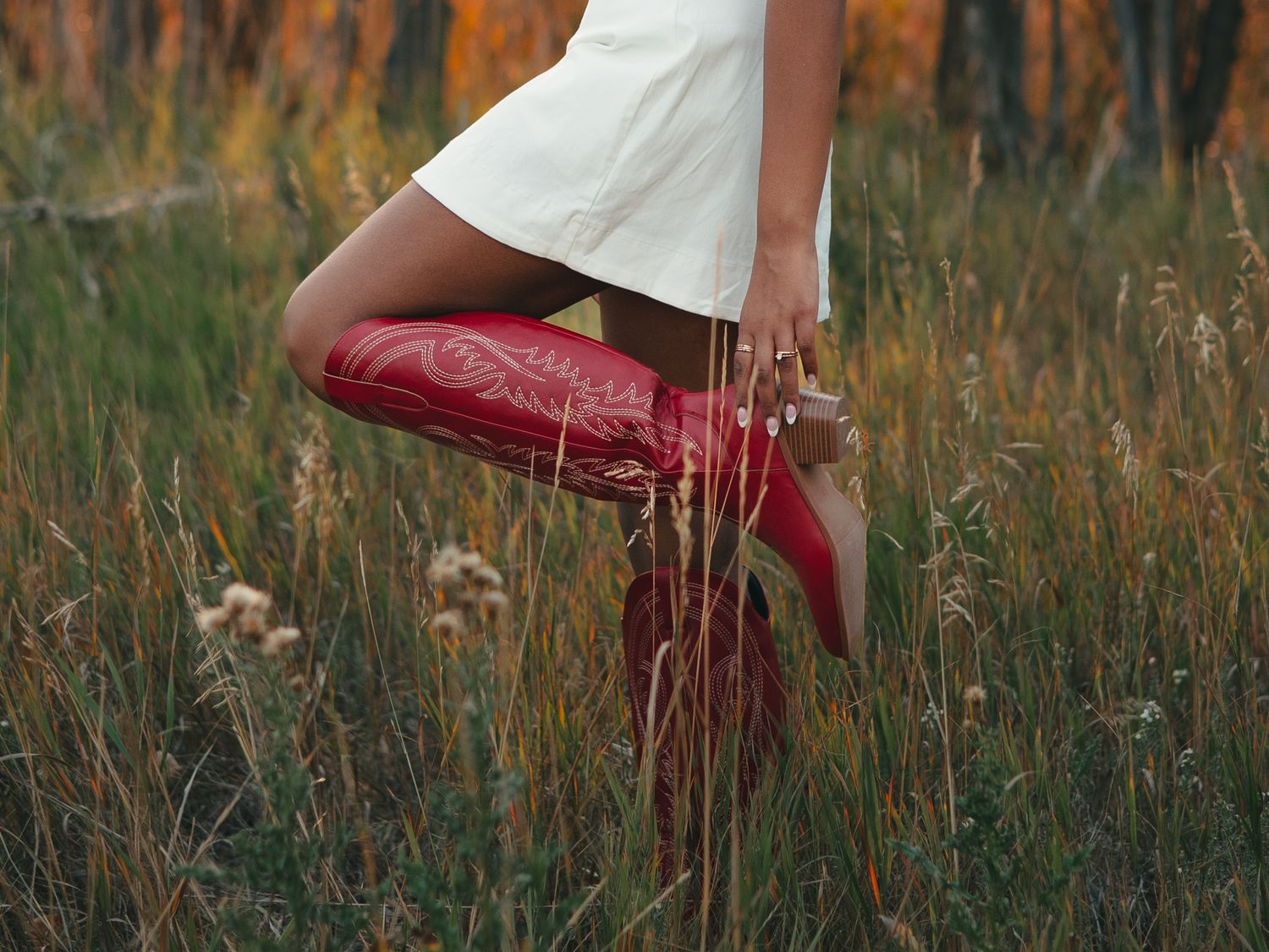 Red boots stand out against tall grass in a dreamy autumn field setting. senior photo, Great Falls, MT