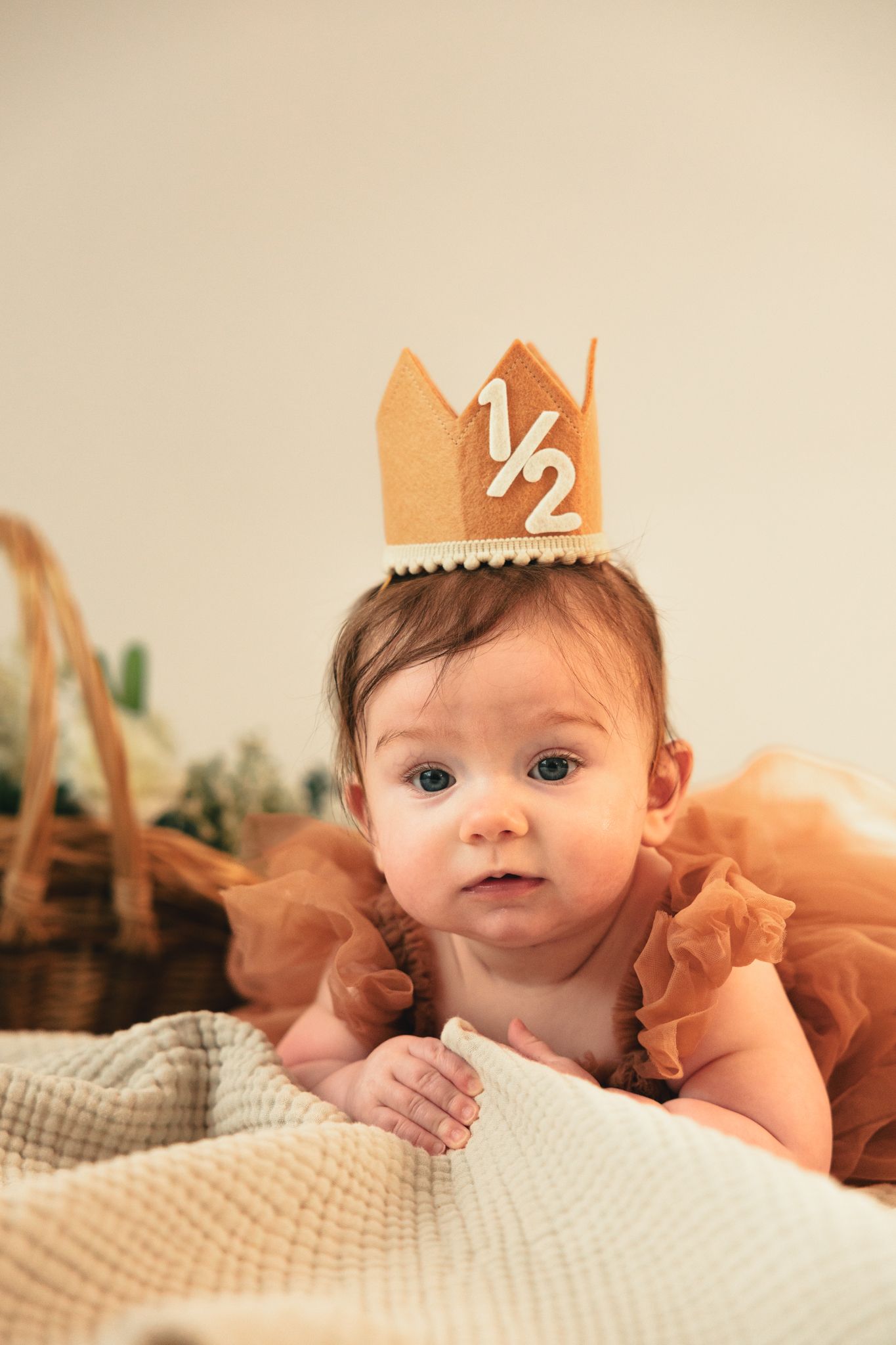 Baby girl in orange tutu wearing a felt half birthday crown celebrating her 6 month milestone.