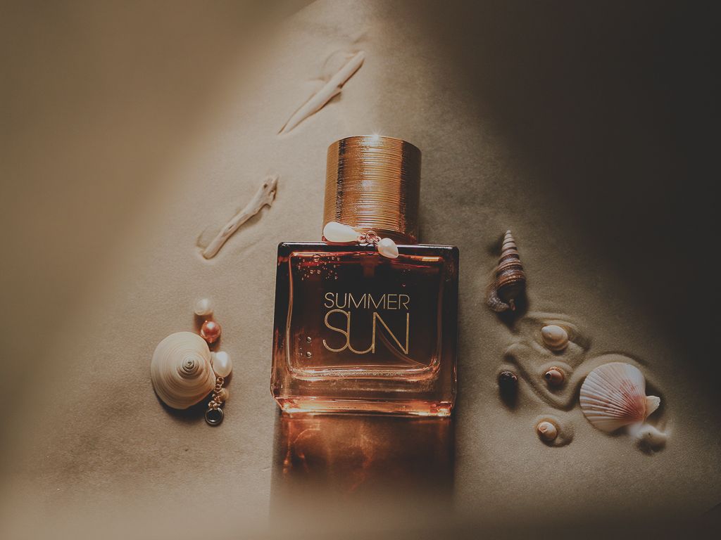 Luxury perfume bottle labeled 'Sun' styled with small decorative skulls in a moody artistic composition.