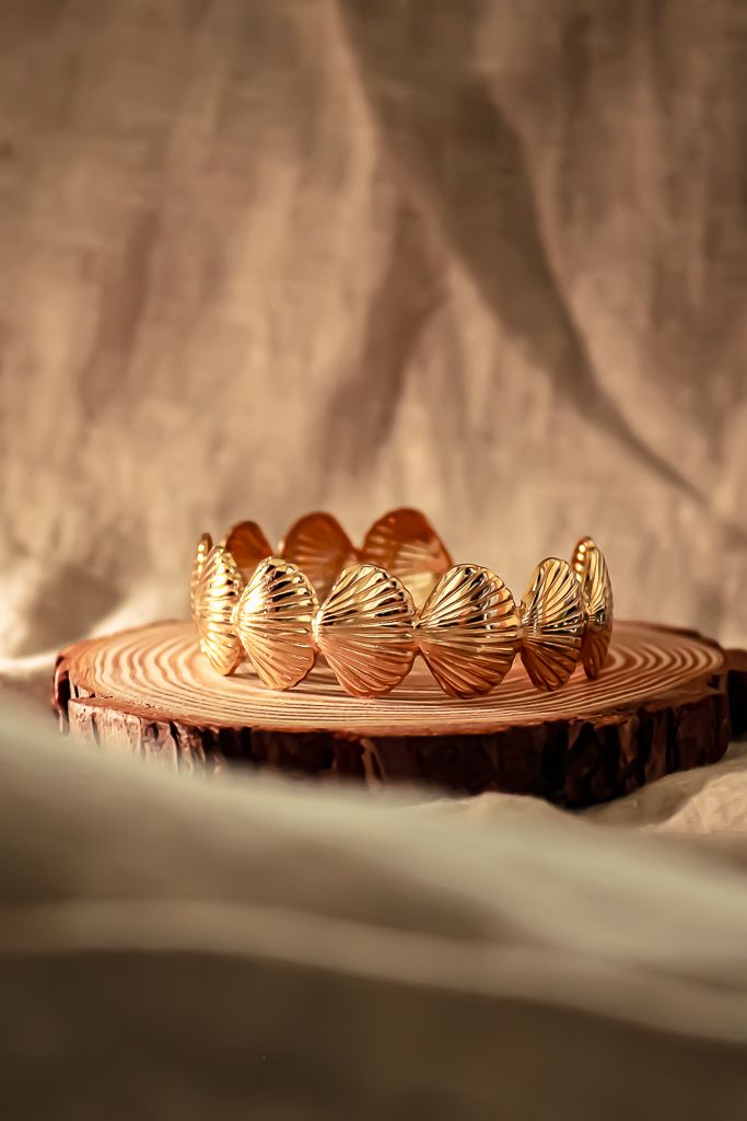 Decorative golden butterfly crown displayed on a rustic wooden slice with dramatic lighting.
