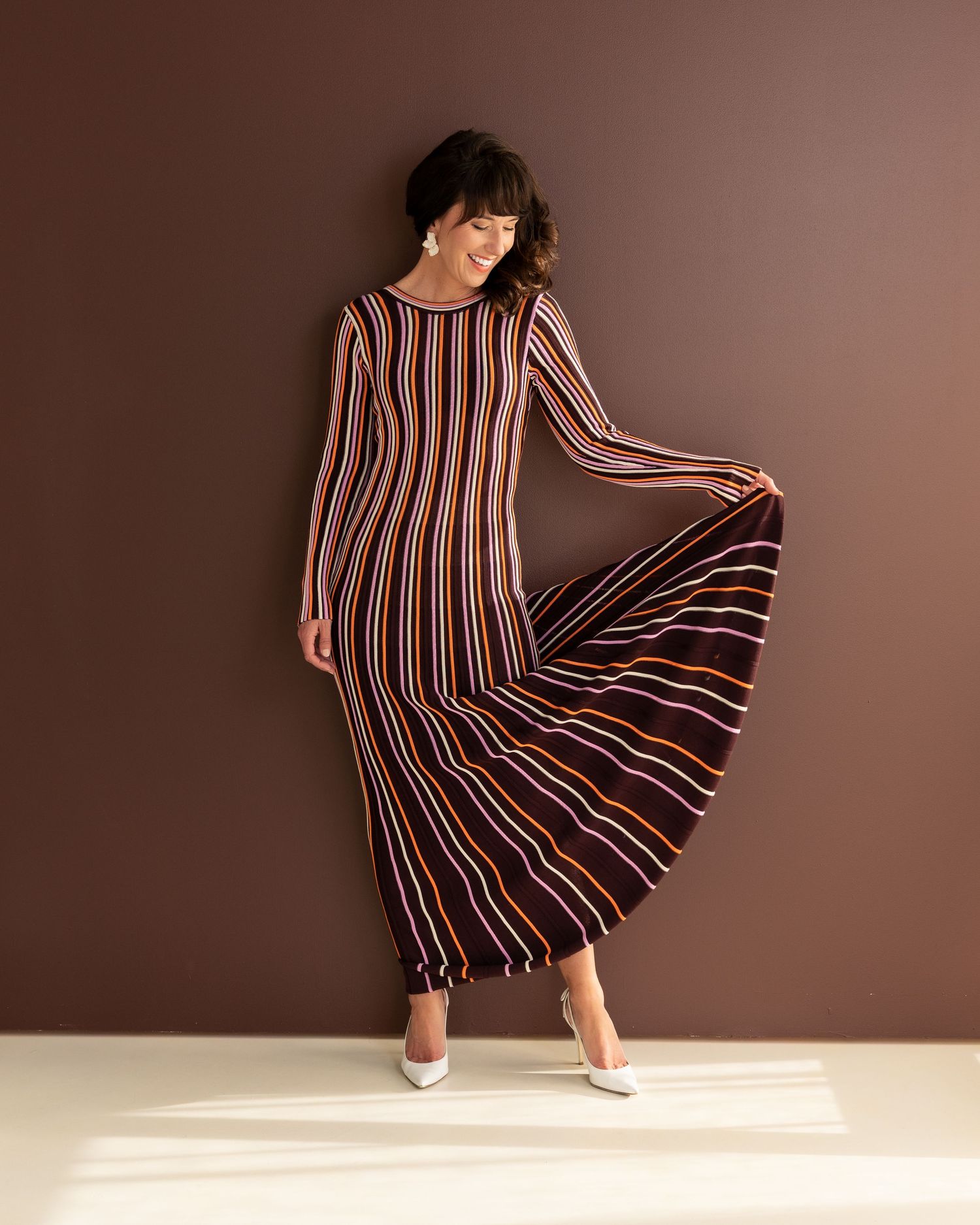 Fashion sequence featuring striped dress with flowing movement against brown backdrop.