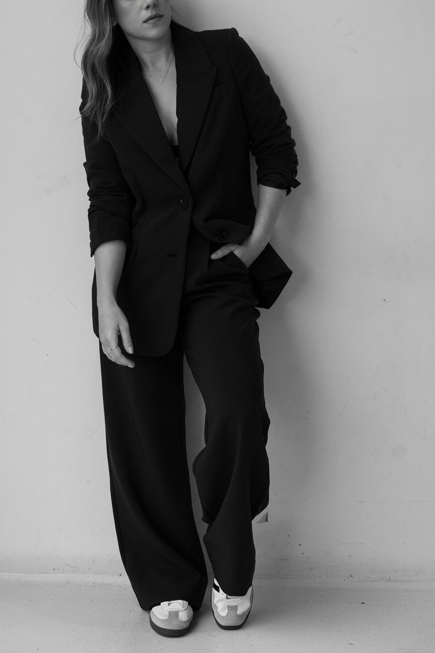 Black and white full-length shot of a woman in a black oversized blazer and wide-leg trousers.