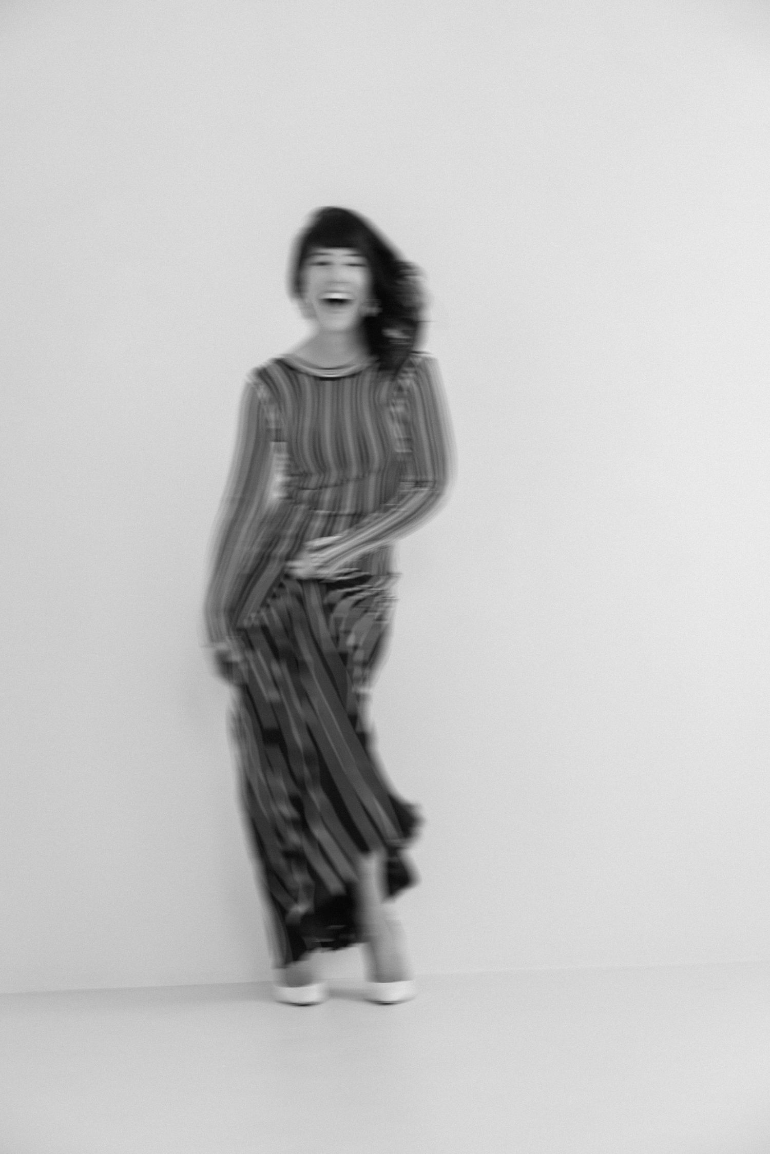 A sequence of black and white photos showing a figure in striped clothing performing dance-like movements against a white background.