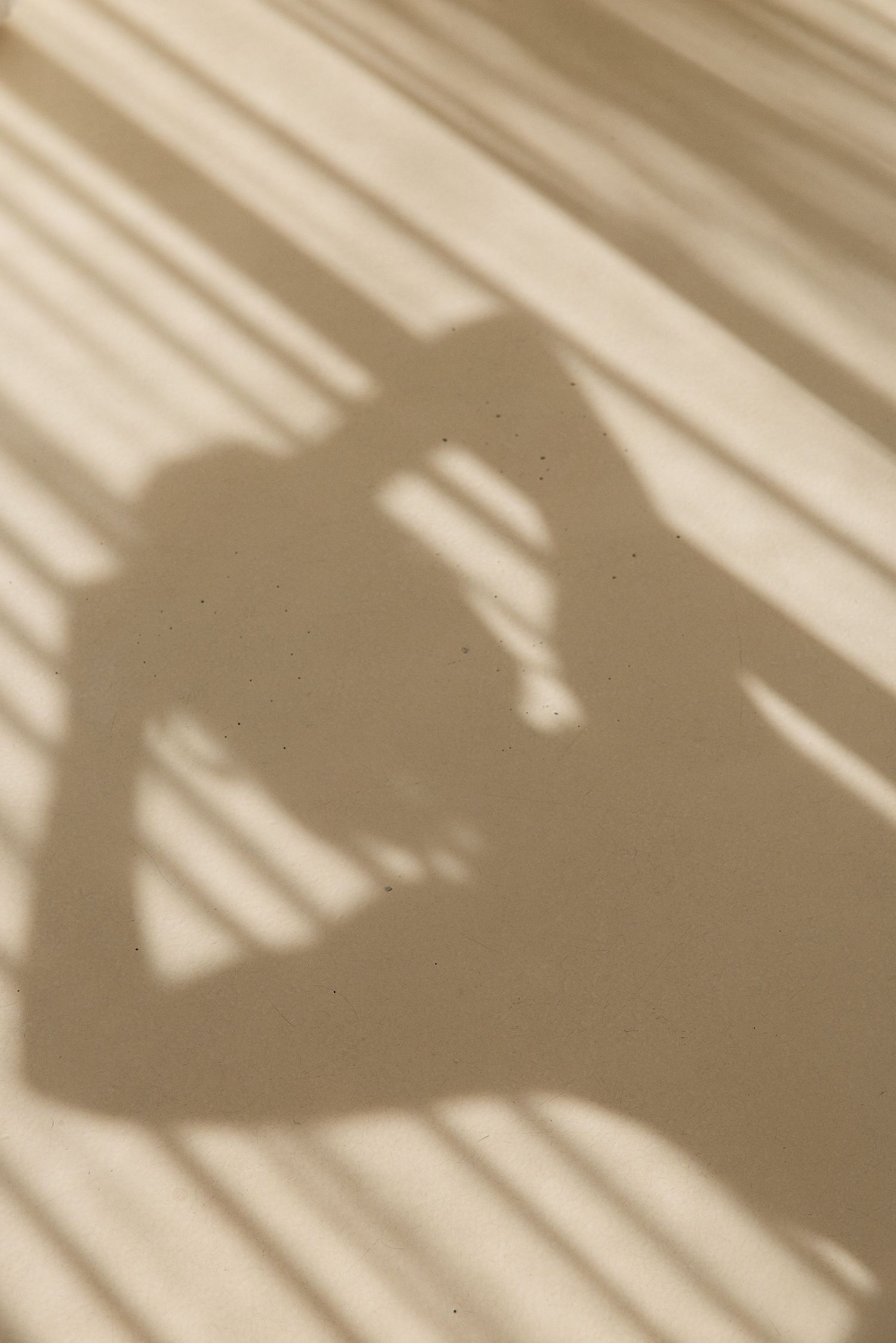 Artistic shadow silhouette of a person cast on a striped beige surface.