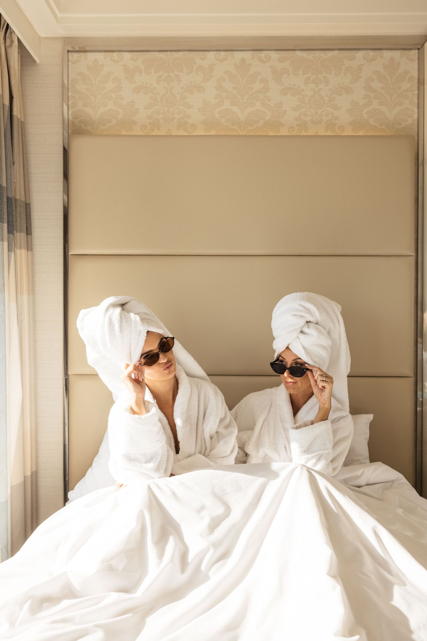 Several figures wrapped in white sheets and sunglasses posed in a row on a couch.