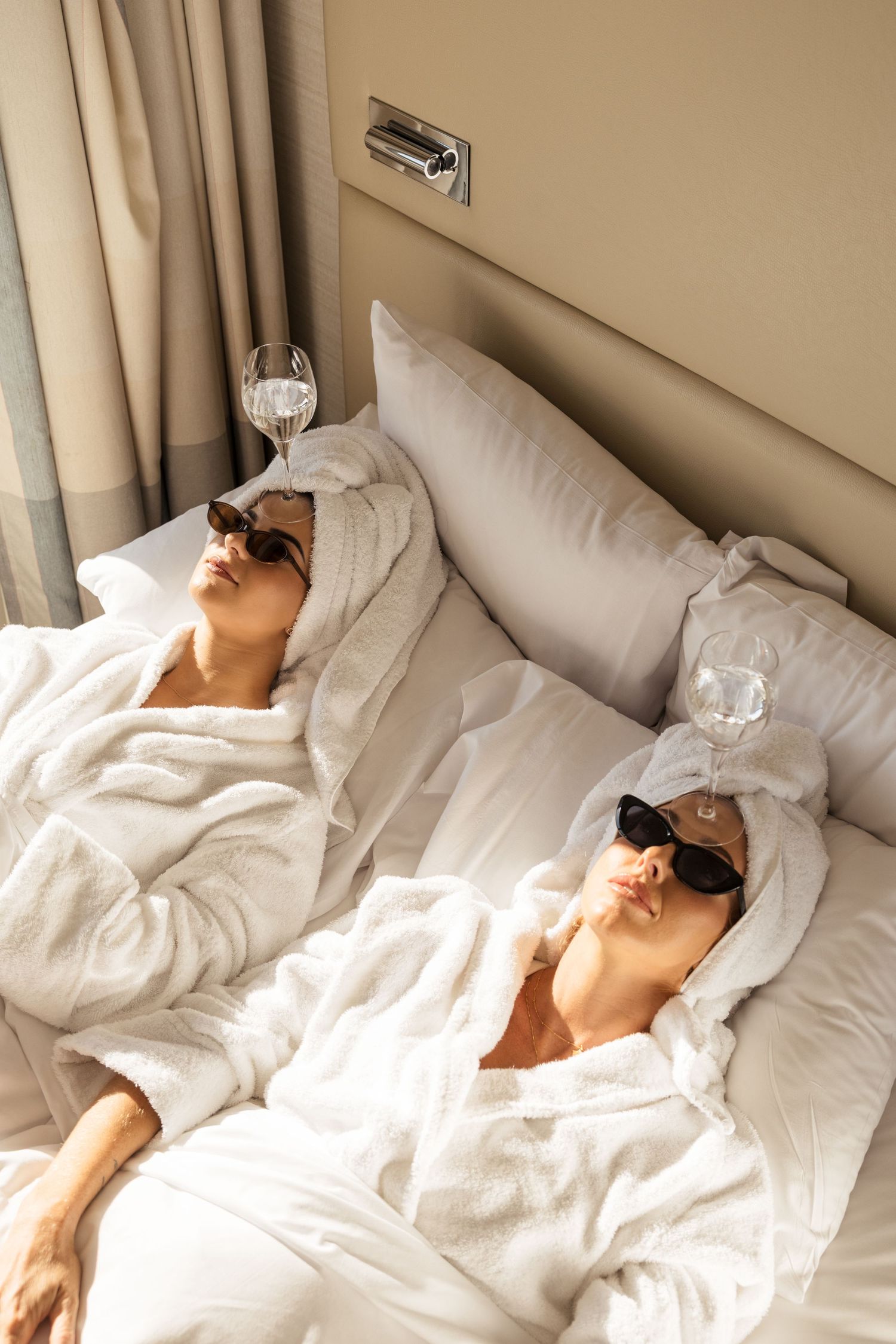Person sleeping peacefully in white hotel bedding wearing sunglasses.