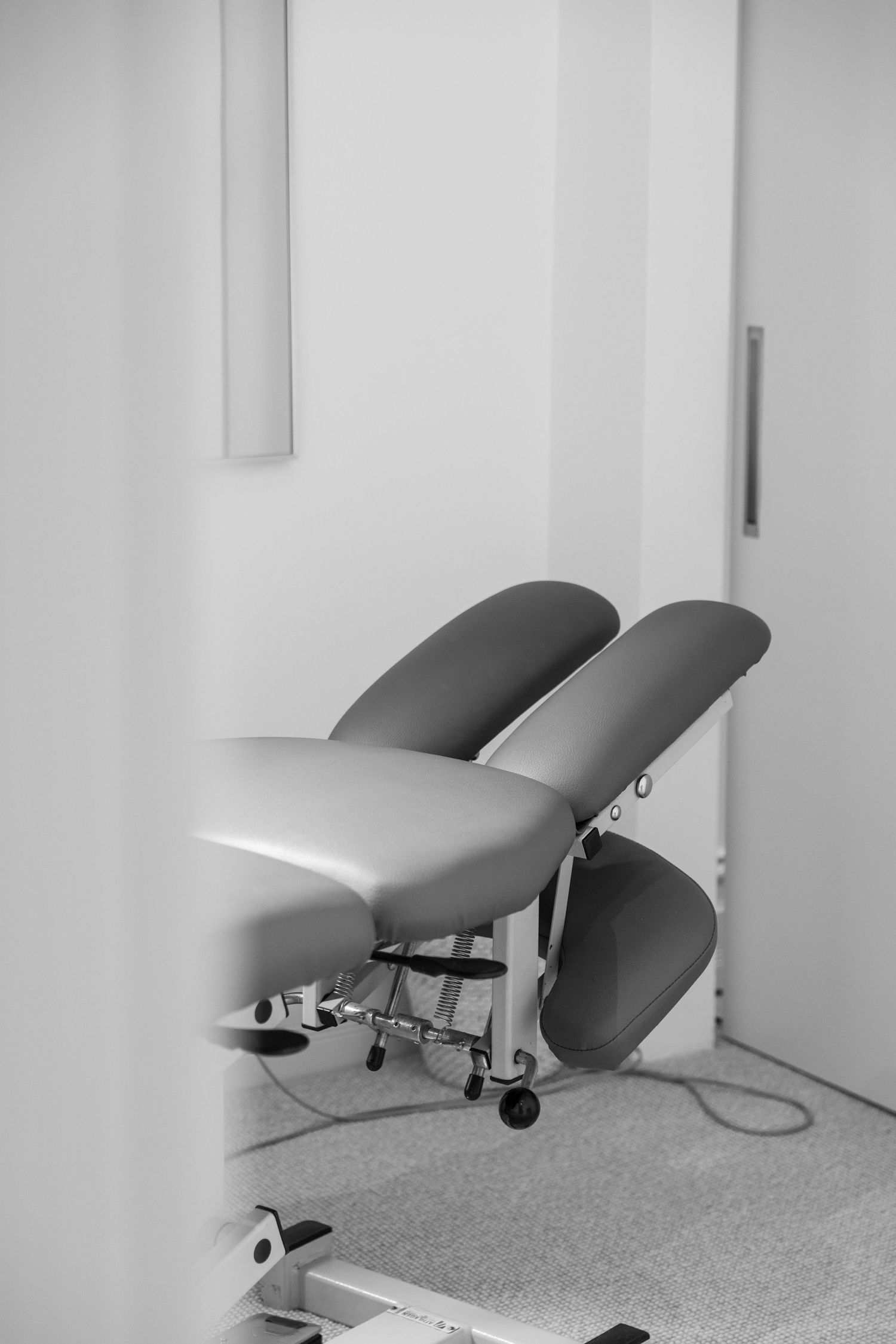 Black and white photo of a professional chiropractic adjustment table in a clean clinic room.