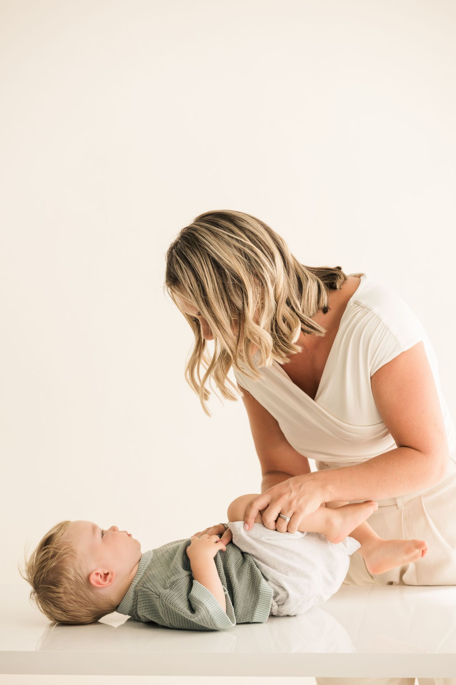Series of tender moments captured in minimalist white studio setting with baby in grey clothing.