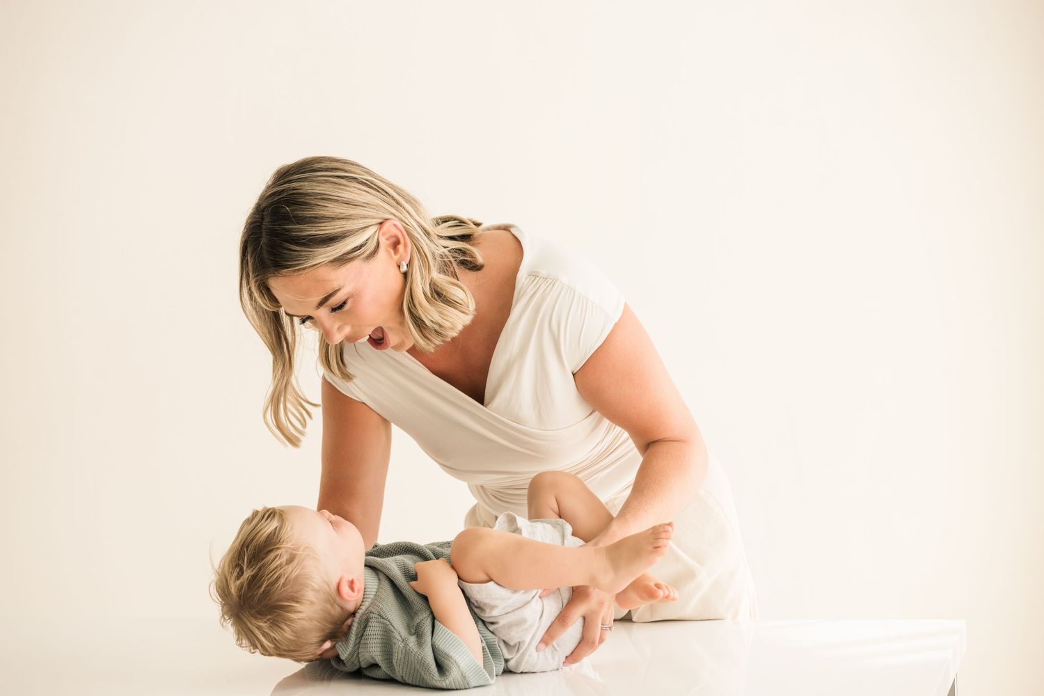 Woman in white dress holding and embracing young child in tender moment.
