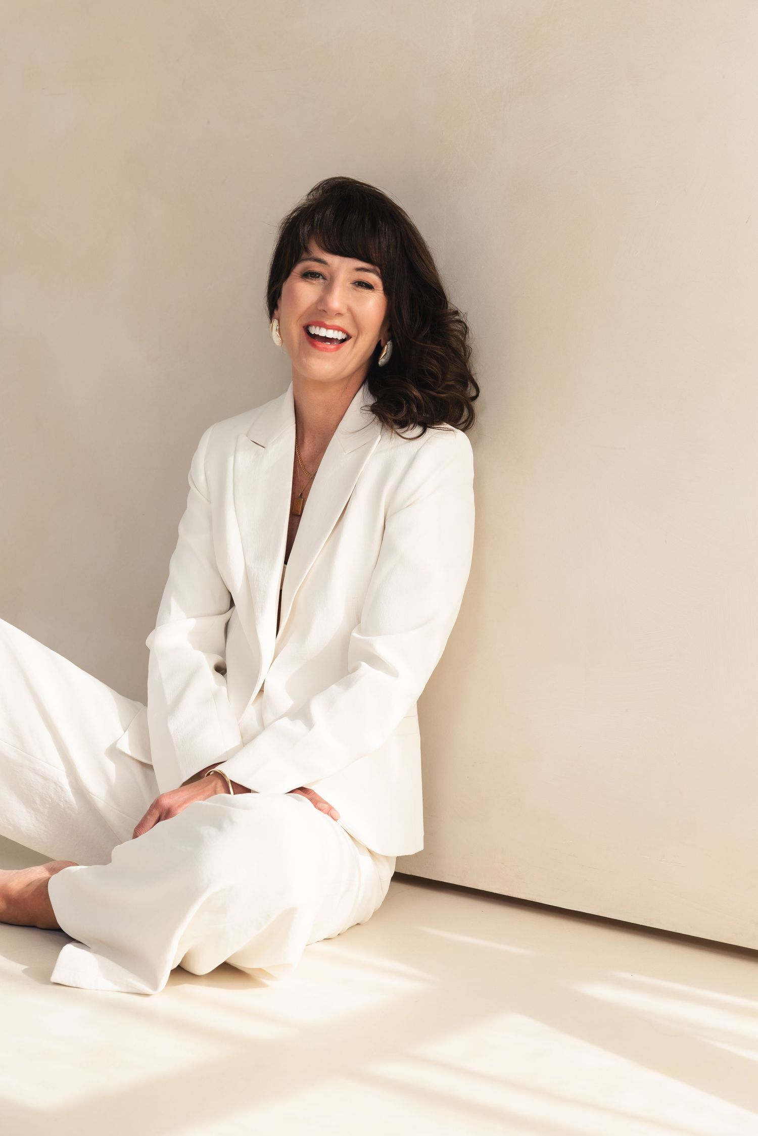 A white blazer ensemble is captured in candid poses against a bright minimal backdrop.
