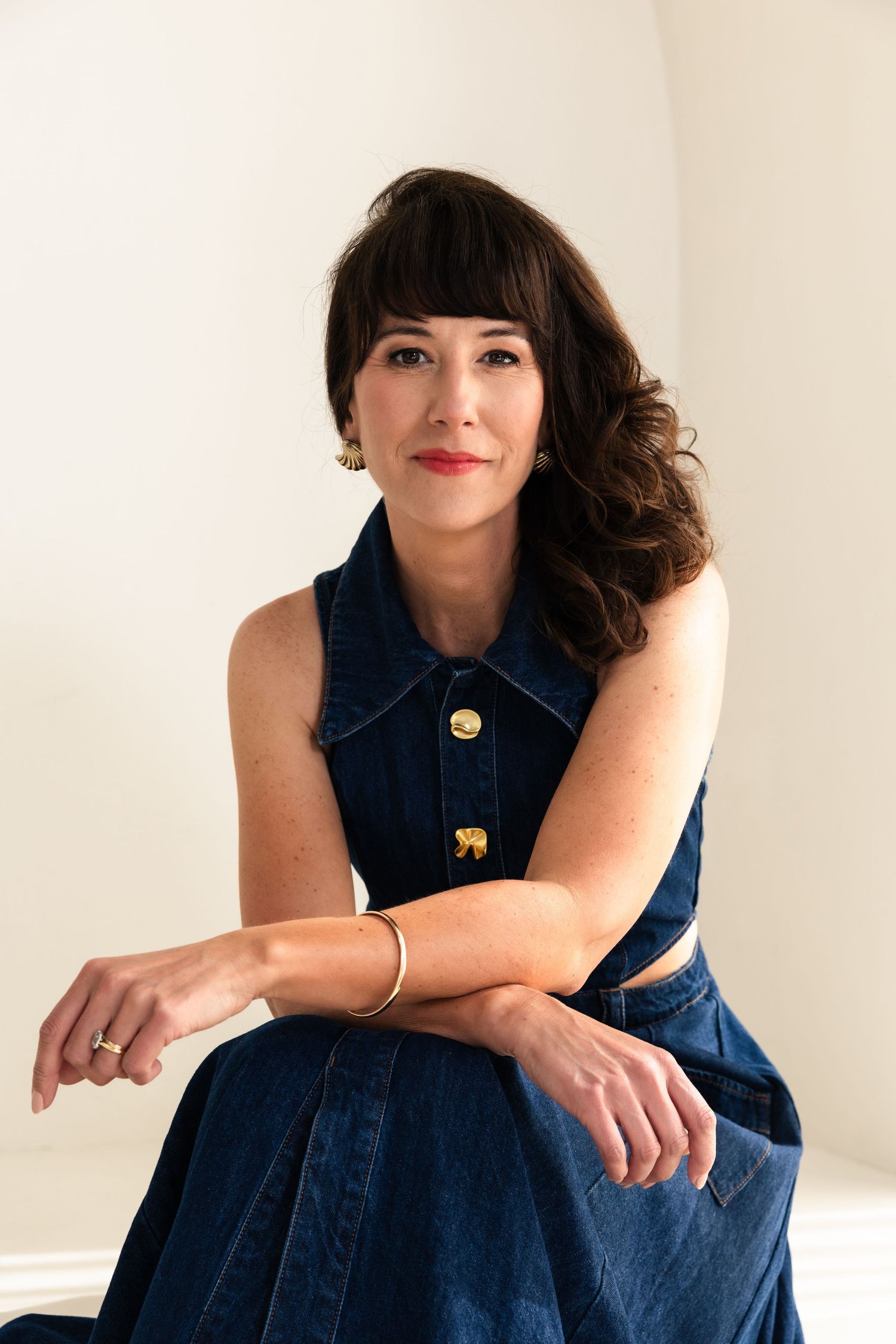 A denim dress with gold buttons is showcased in various poses against a white backdrop.