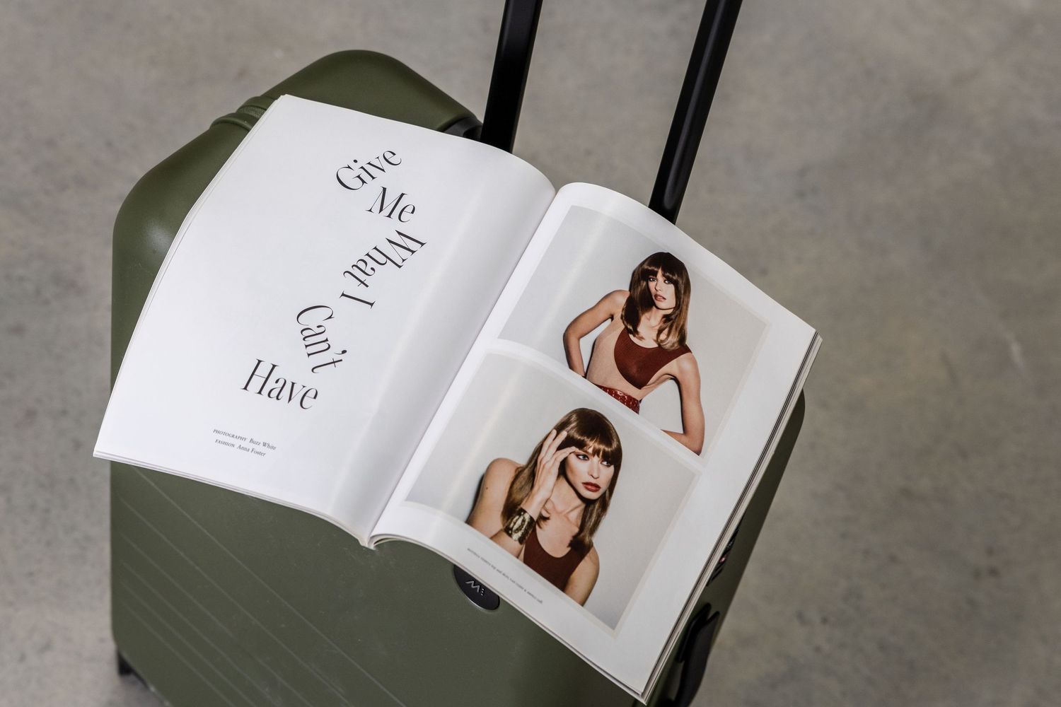 Open fashion magazine displaying editorial spreads on gray surface.
