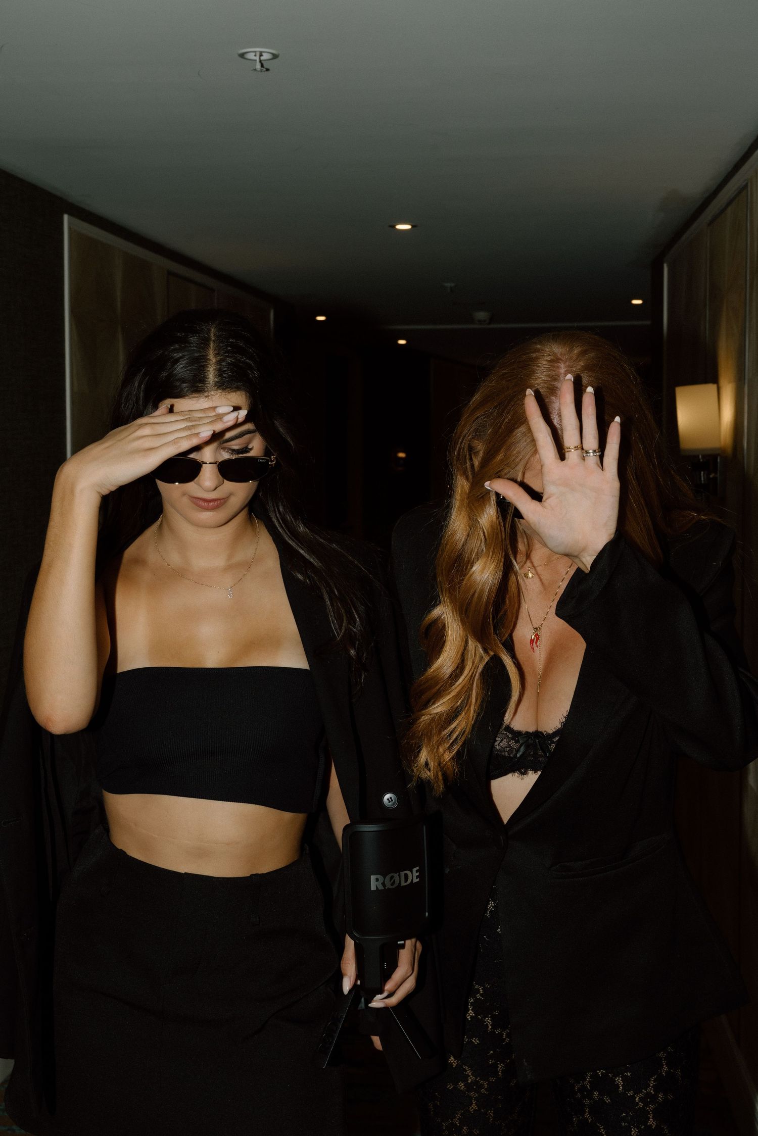 People in dark clothing walking through a dimly lit hallway covering their faces.
