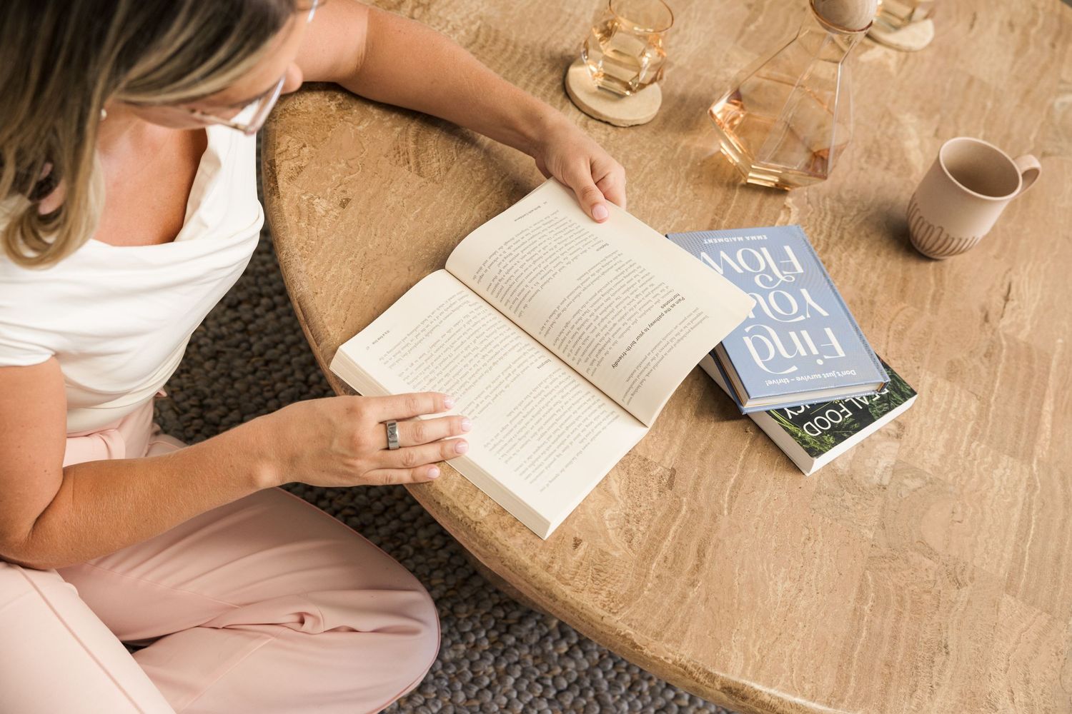 Students studying together at wooden table with books and coffee cups, viewed from above.